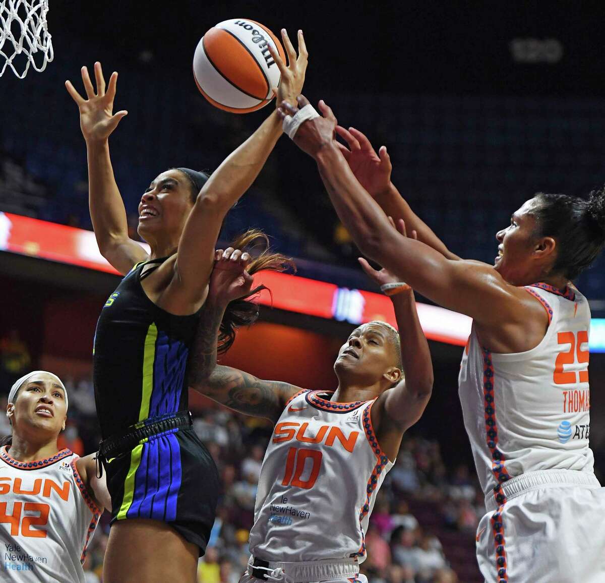 Dallas Wings forward Isabelle Harrison, second from left, battles against Connecticut Sun forward Alyssa Thomas (25), guard Courtney Williams (10), and center Brionna Jones (42) for a rebound during Game 1 of a WNBA basketball first-round playoff series Thursday, Aug. 18, 2022, in Uncasville, Conn. (Sean D. Elliot/The Day via AP)