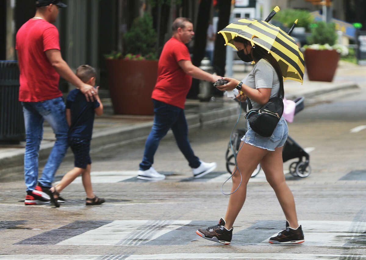 A pedestrian shields herself from rain with an umbrella in downtown San Antonio in 2021. San Antonio could see chances of rain every day this week. 