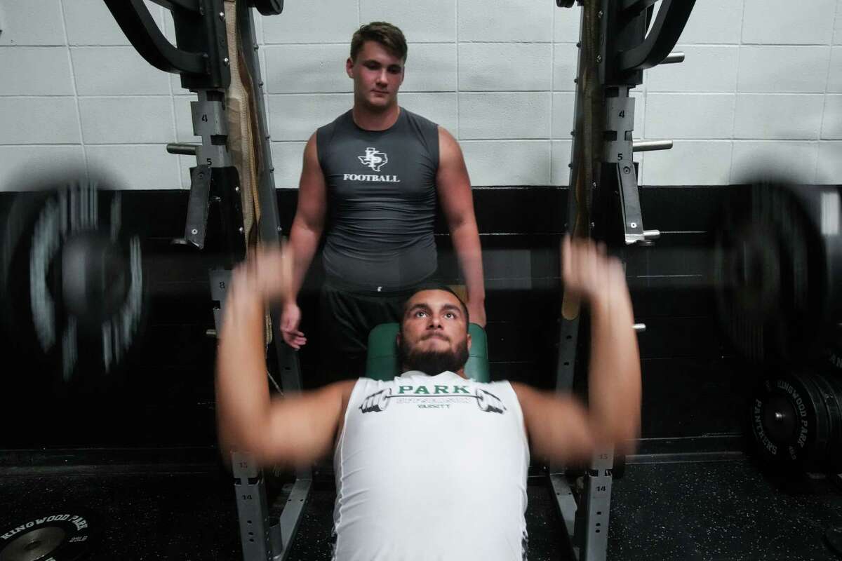 Kingwood Park guard Trent Savage spots offensive lineman Erick Zapata as he lifts in the weight room after school Wednesday, Aug. 17, 2022 in Kingwood.
