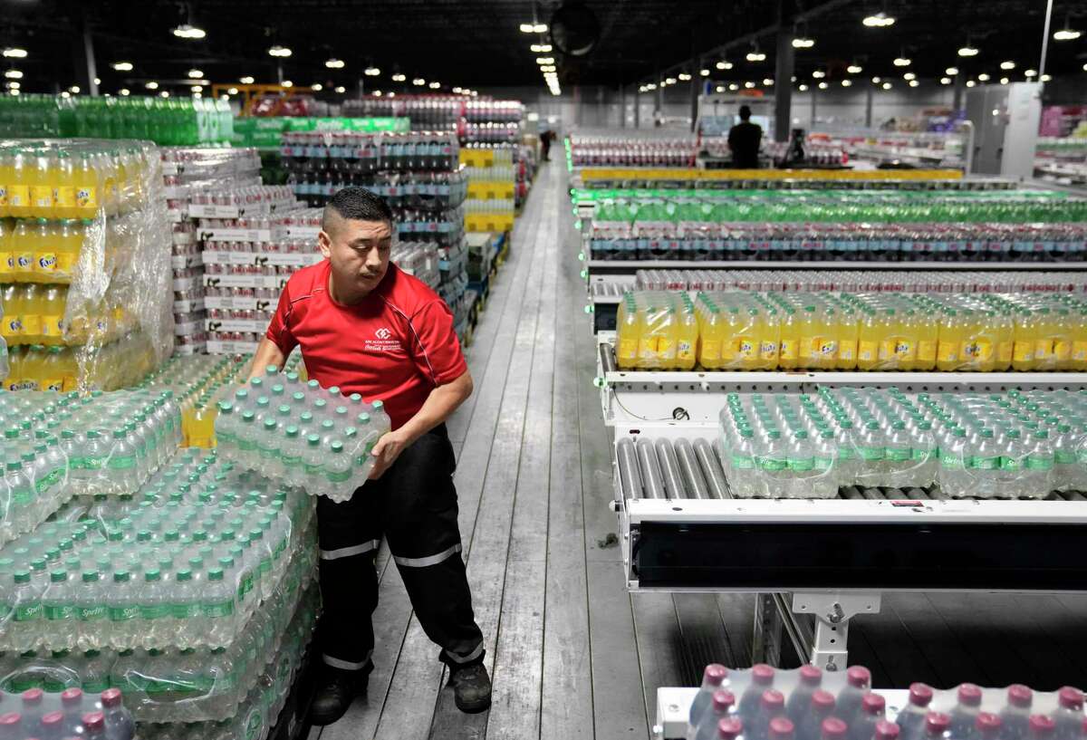 Alberto Gutierrez places cases of products onto conveyors at the Arca Continental Coca-Cola Southwest Beverages Northpoint Bottling Plant, 10475 Deer Trail Dr., Thursday, Aug. 18, 2022, in Houston.