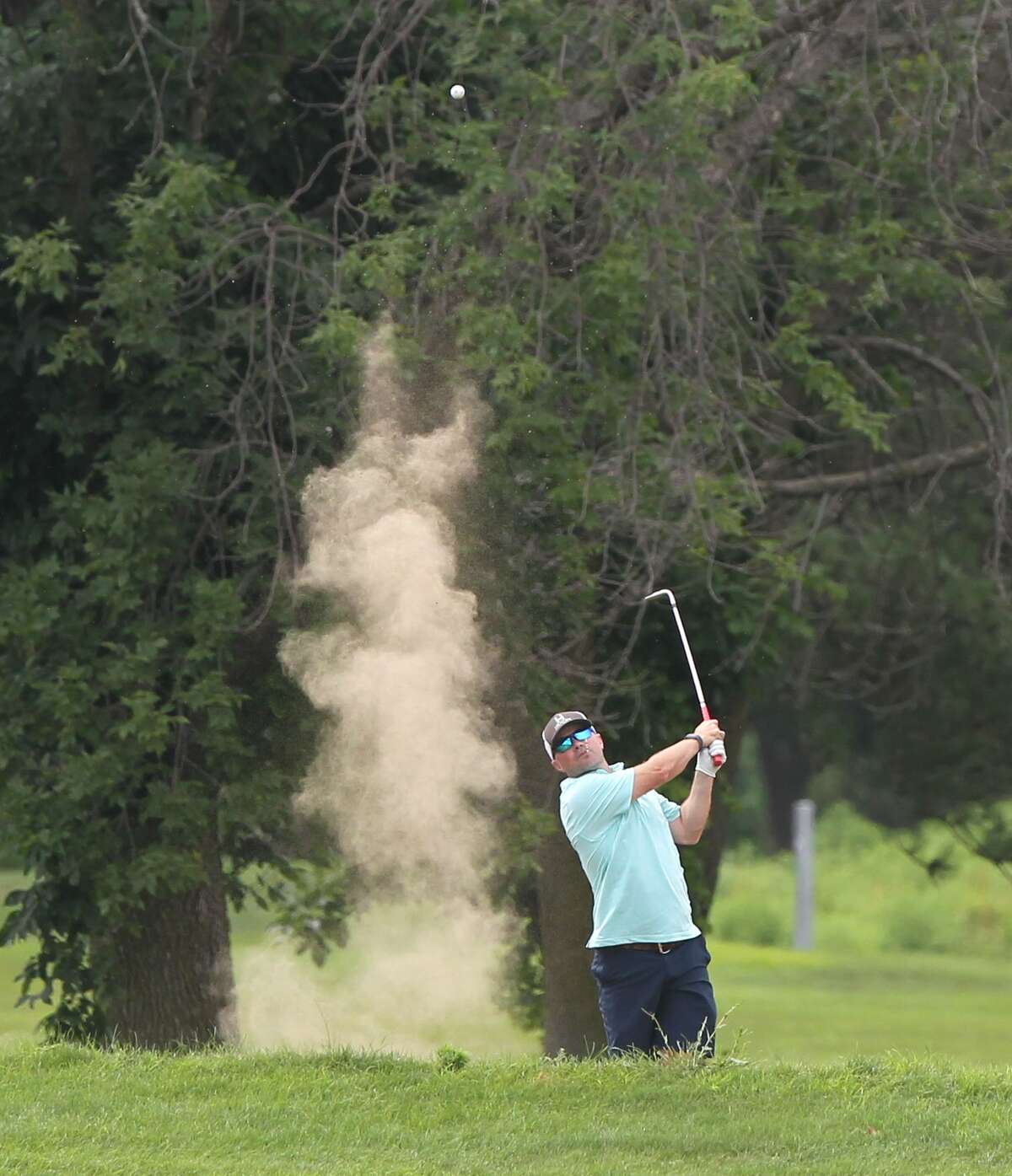 A golfer kicks up a little dust as he blasts out of a sand trap during a recent round at The Links Golf Course.