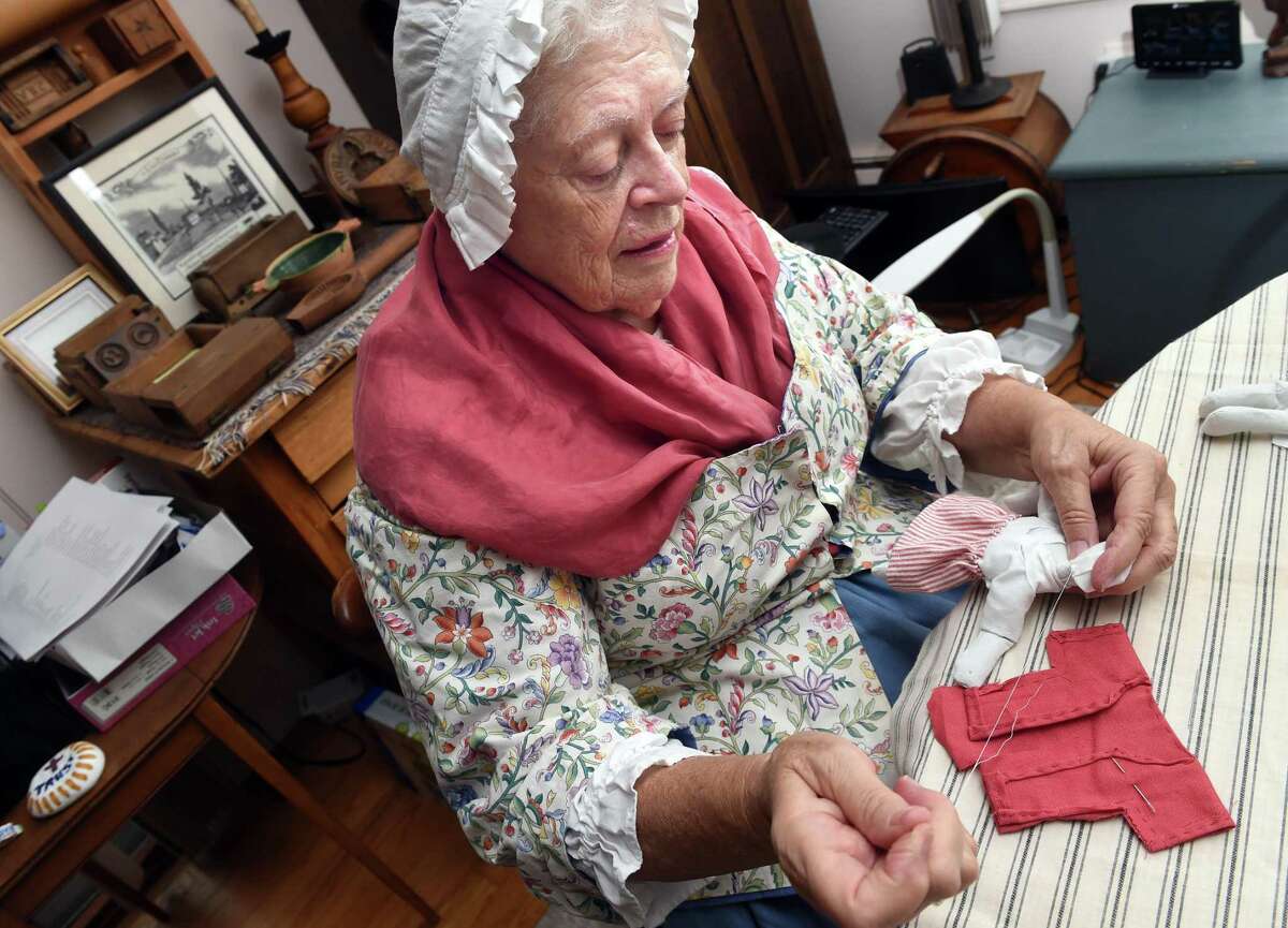 Reenactor Barbara Cubberly stitches 1750’s-style French doll clothes at her home in Clinton.