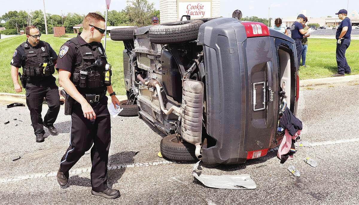 Alton Police officers examine an overturned Jeep Patriot Friday afternoon after it collided with a BMW 335i and flipped over on Alby Street at East Center Drive. Miraculously nobody was injured in the crash. Traffic in the area was disrupted for a while.