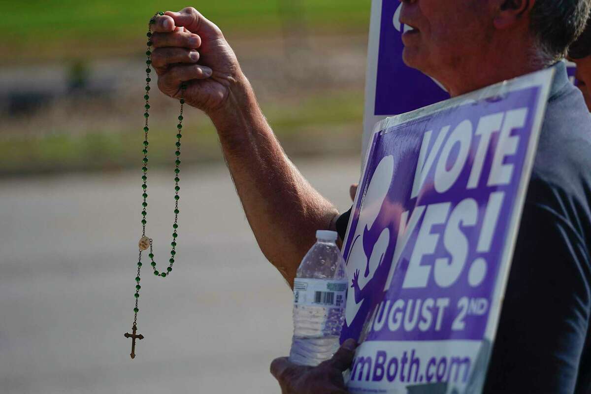 Deacon John Stanley of the Catholic Church and Connie Stanley pray and wave at cars while holding signs in support of the Vote Yes to a Constitutional Amendment on Abortion along 135th Street on Aug. 1, 2022, in Olathe, Kansas. (Kyle Rivas/Getty Images/TNS)