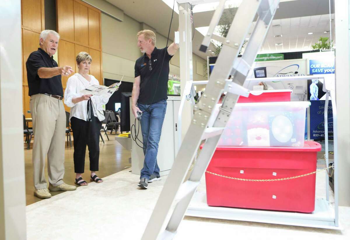Kevin Hassell, right, talks to a couple about automatic lifts for storage during the annual Montgomery County Home and Outdoor Living Show at the Lone Star Convention & Expo Center, Saturday, Aug. 20, 2022, in Conroe.