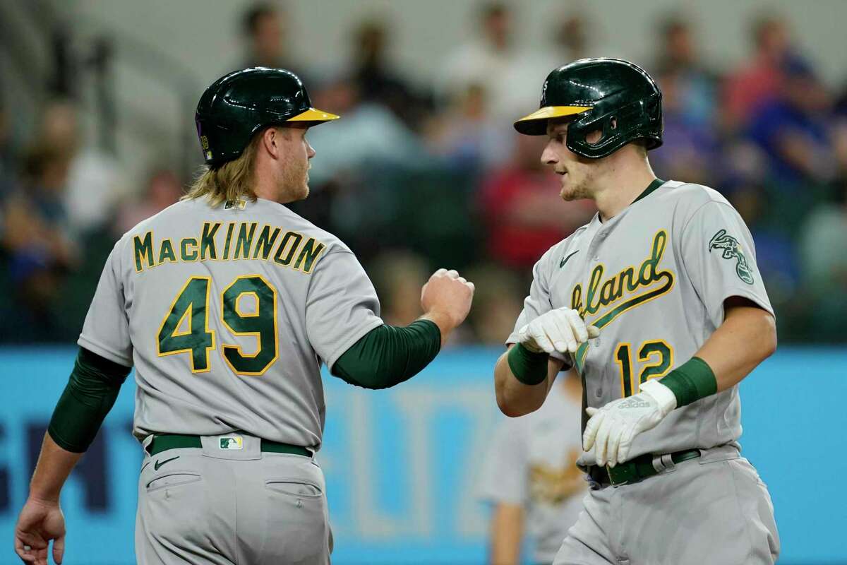 Oakland Athletics' David MacKinnon (49) and Sean Murphy (12) celebrate Murphy's two-run home run that scored MacKinnon in the fourth inning of a baseball game against the Texas Rangers, Wednesday, Aug. 17, 2022, in Arlington, Texas. (AP Photo/Tony Gutierrez)