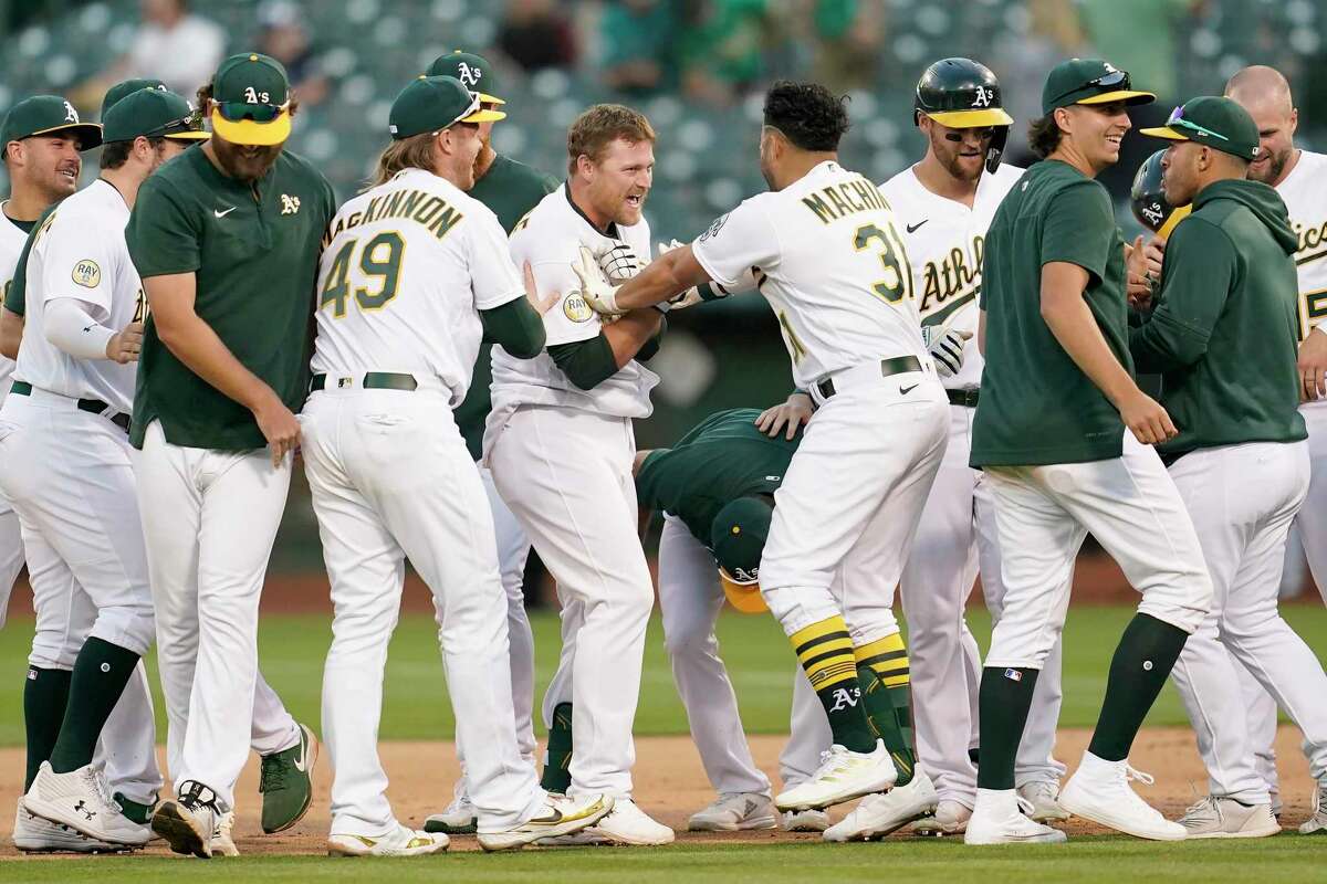Oakland Athletics' Sheldon Neuse, center, is congratulated by teammates after hitting into a fielder's choice that scored Tony Kemp during the 10th inning of a baseball game against the Seattle Mariners in Oakland, Calif., Saturday, Aug. 20, 2022. (AP Photo/Jeff Chiu)