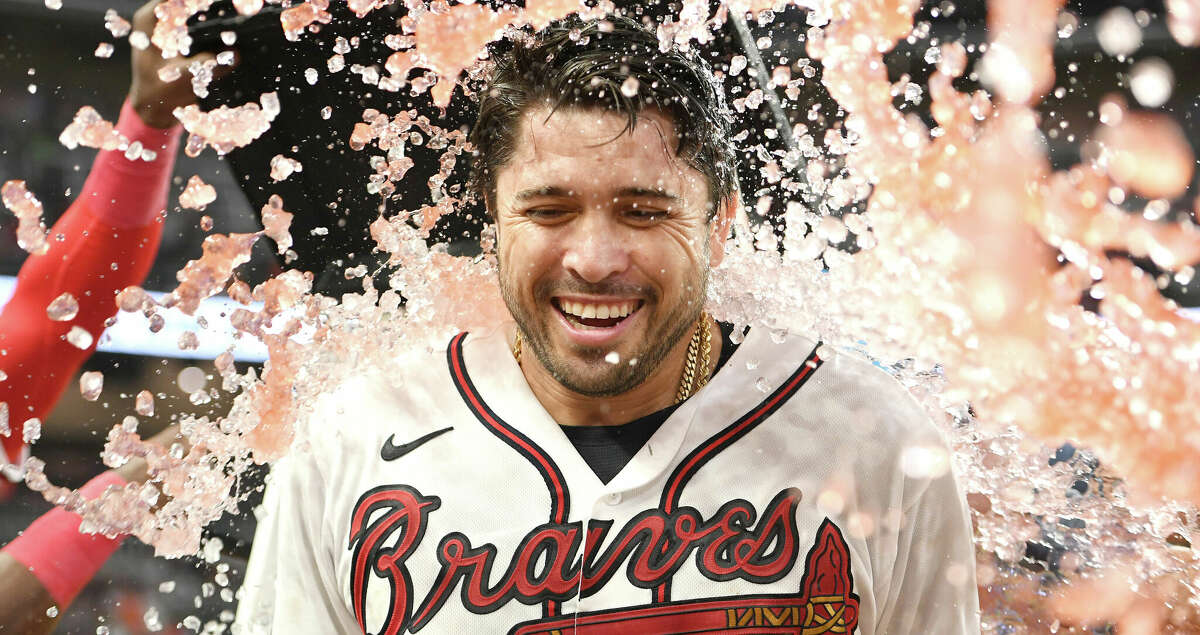 Travis d'Arnaud #16 of the Atlanta Braves gets a Gatorade bath by teammates after hitting a walk off single against the Houston Astros during the eleventh inning at Truist Park on August 20, 2022 in Atlanta, Georgia. (Photo by Adam Hagy/Getty Images)