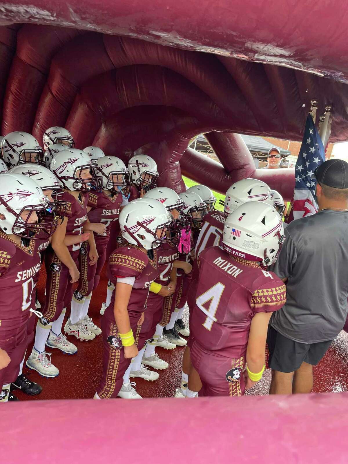 The Junior Deer Park Seminoles wait in the team's giant  helmet Saturday, before taking the field for their season opener against the Friendswood Colts.