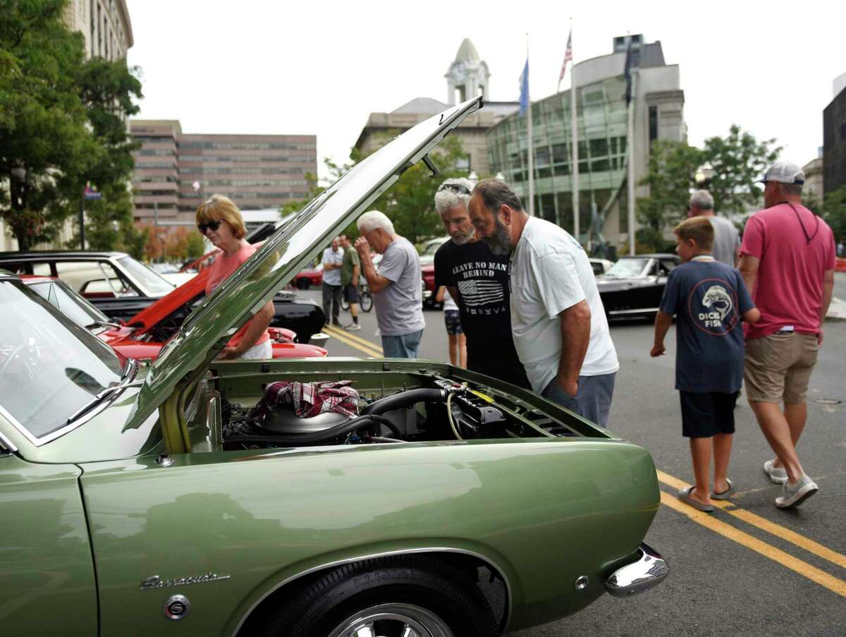 Stamford's Rick Preli, left, and Mike Mammone look under the hood of a vintage Plymouth Barracuda on display at the Cruising Stamford auto show Sunday at Columbus Park in Stamford.