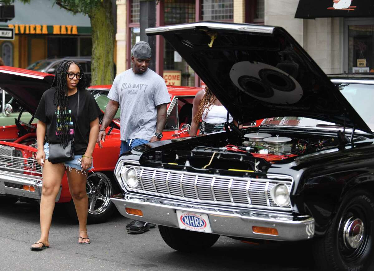 Jeanette Brown, of Philadelphia, and Andy Mitchell, of Trumbull, look at a vintage 1964 Plymouth on display at the Cruising Stamford automobile show at Columbus Park in Stamford, Conn. Sunday, Aug. 21, 2022. More than 150 vintage through early-'80s cars were on display on Main Street, featuring live music, outdoor dining, face painting, prizes, and more. The event, now in its second year, was presented by First Bank of Greenwich, Synergy1Holdings, and BlackRoads Auto Club to honor Eversource Energy and the U.S. Postal Service.