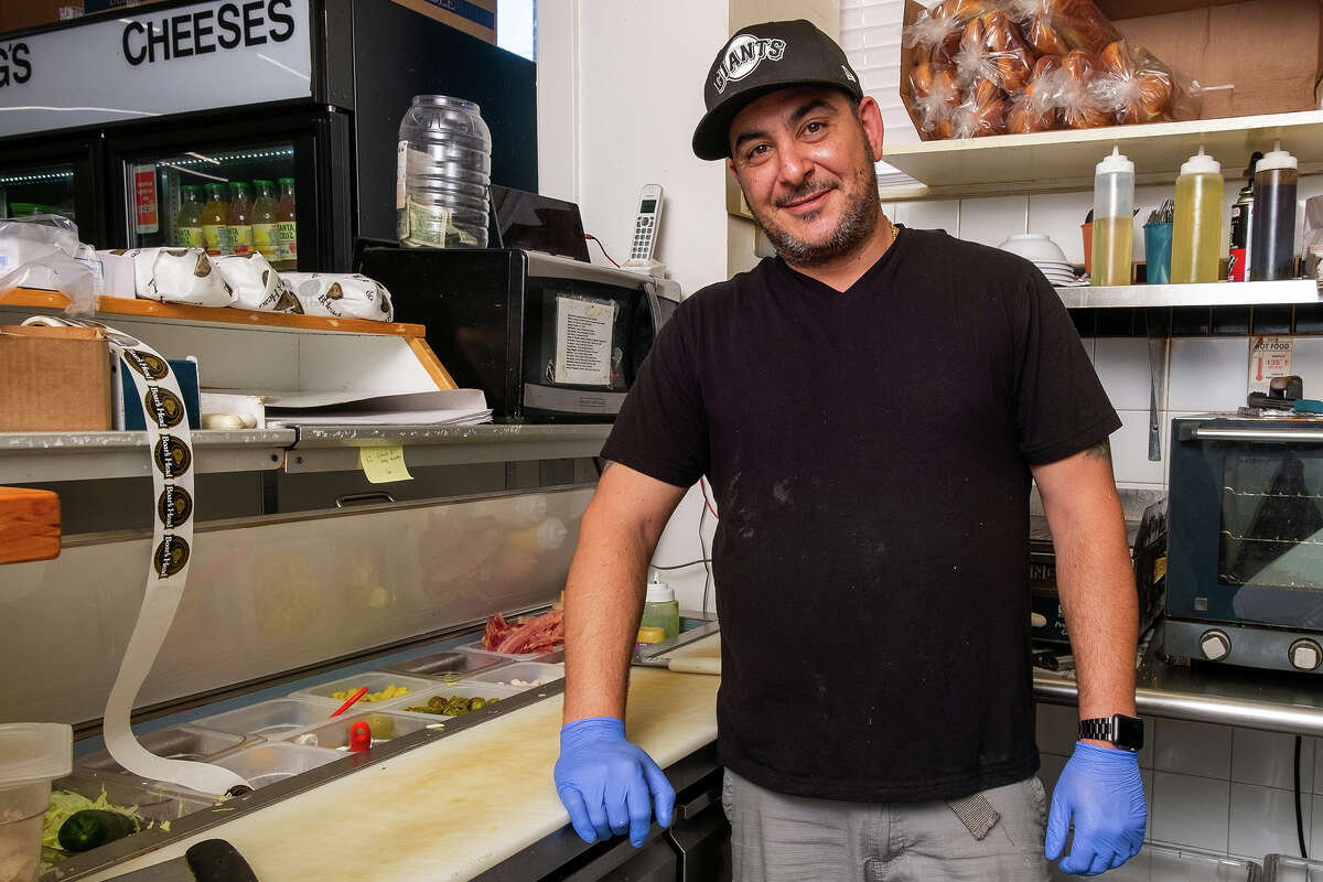 Joey Jada, owner of McBaker Market & Deli, takes a moment for a portrait while gearing up for the lunch rush late Friday morning, August 12, 2022.