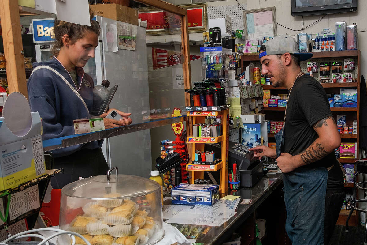 Louie Jada, left, rings up neighborhood local Sarah Dargen at McBaker Market & Deli in San Francisco on Friday afternoon, August 12, 2022.