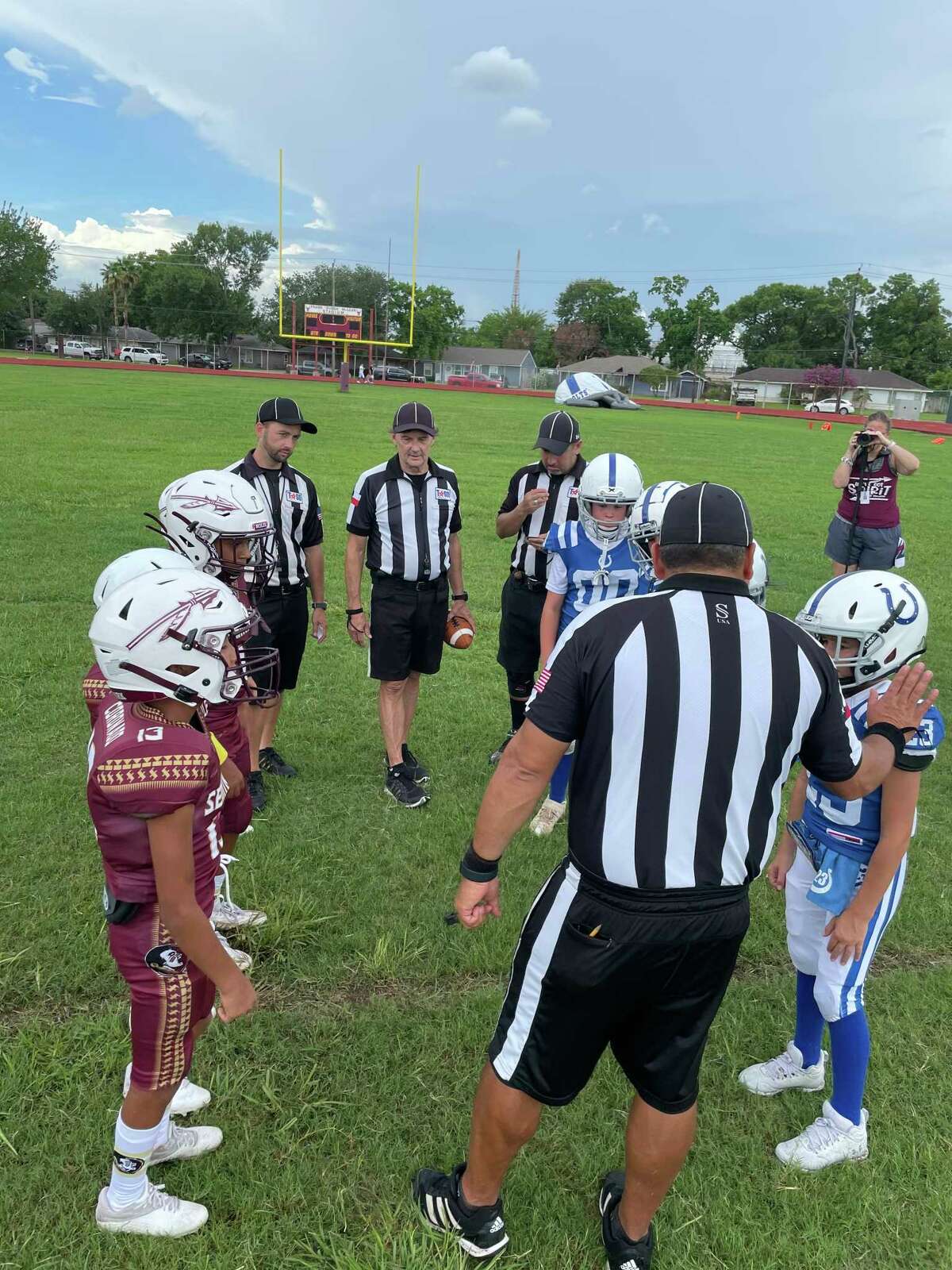 The officiating crew talks to members of the Friendswood Colts and Deer Park Seminoles before the coin toss prior to the Juniors game Saturday afternoon in Deer Park.