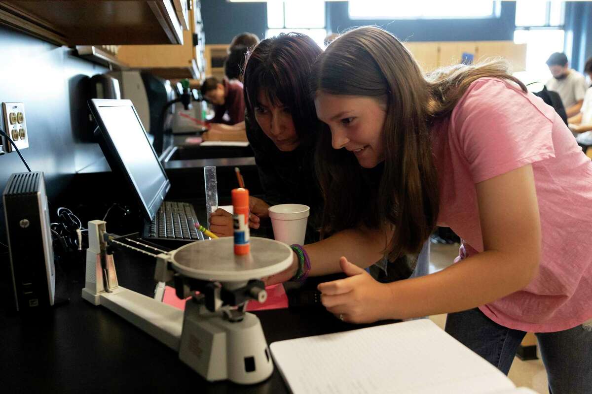 Olivia Bowles and Alley Huffman measure the weight of a glue stick in Shaunna Garner’s 8th grade science class at Tex Hill Middle School. Garner (not pictured) is helping create a new program at Texas Biomedical Research Institute to connect local middle school and high school science teachers with researchers, and to use their work as a teaching tool.