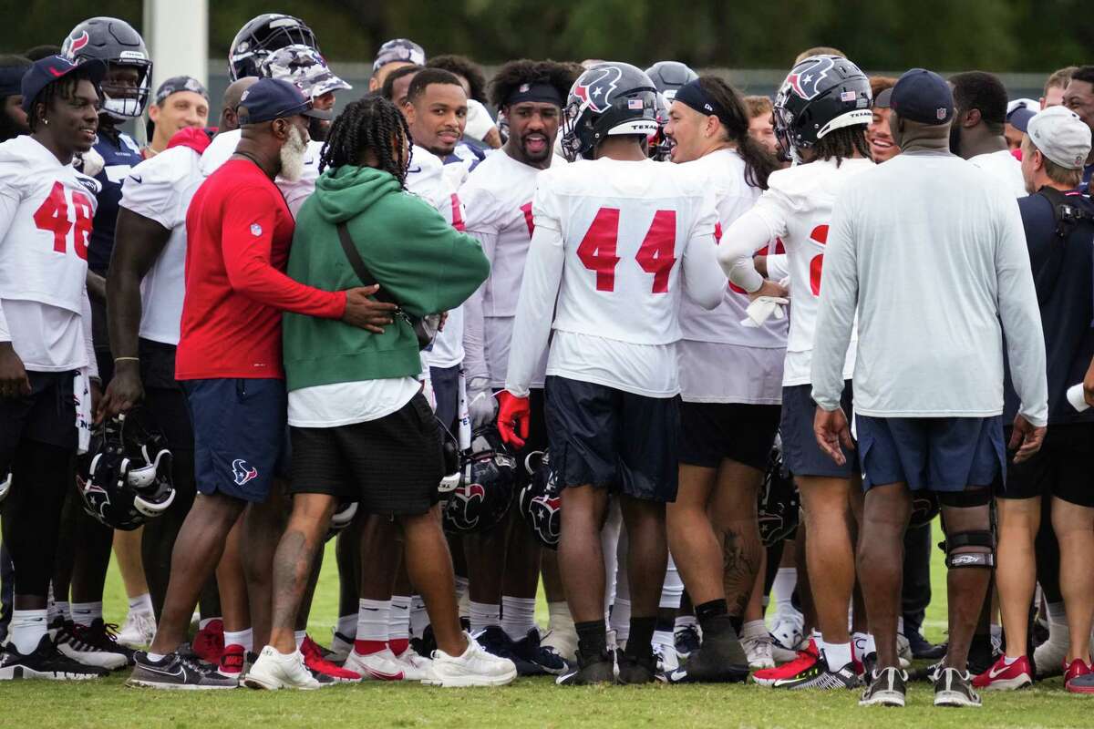 Houston Texans head coach Lovie Smith, left, welcomes rookie wide receiver John Metchie III into the team huddle as the second round draft pick visits training camp for the first time since his cancer diagnosis Tuesday, Aug. 23, 2022, in Houston. The Texans coaches and players have talked about how they’ve wanted to make Metchie feel part of the team each day as he battles leukemia. Metchie got his chance to be there with them on the final day of training camp.
