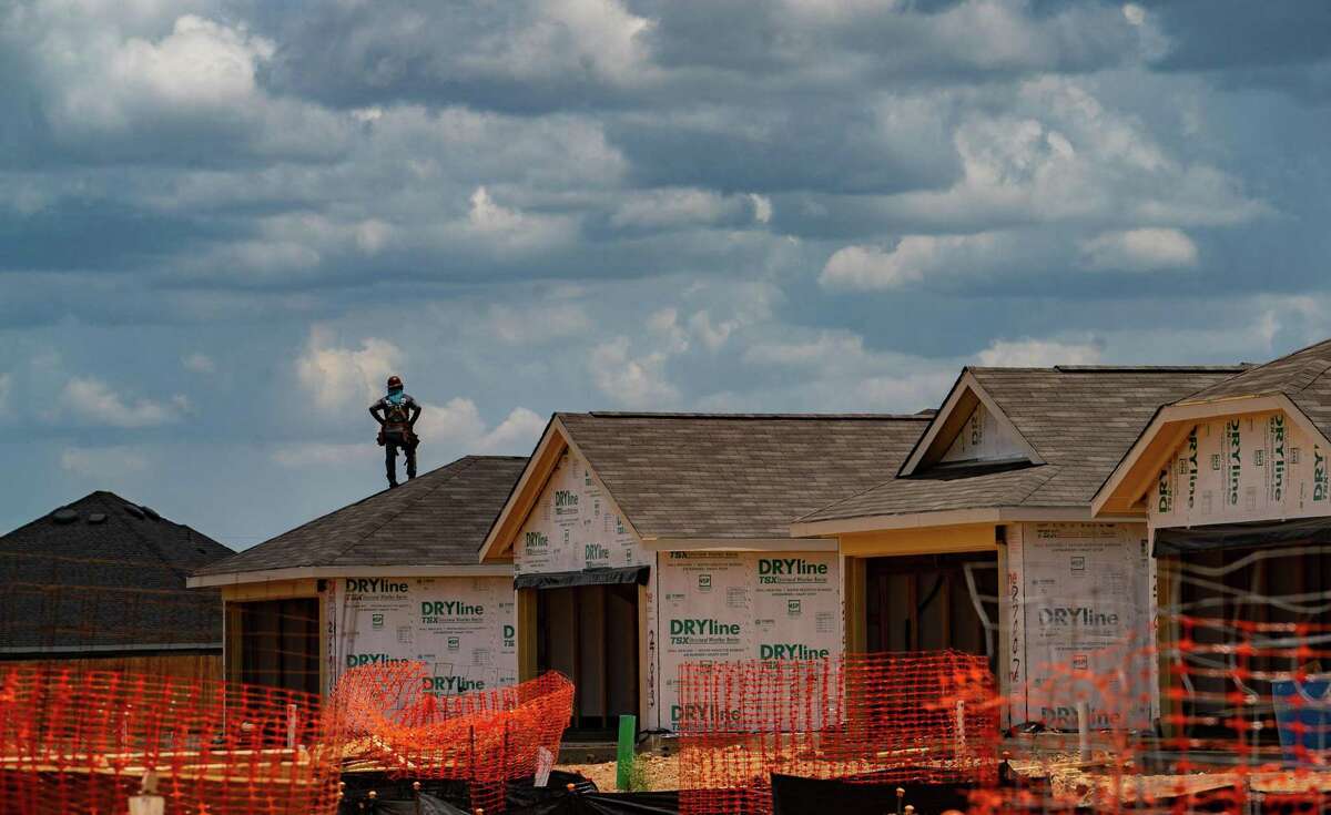 A worker on the roof in new construction going up north of Interstate 10 and west of the Grand Parkway, Thursday, July 7, 2022, in Katy.