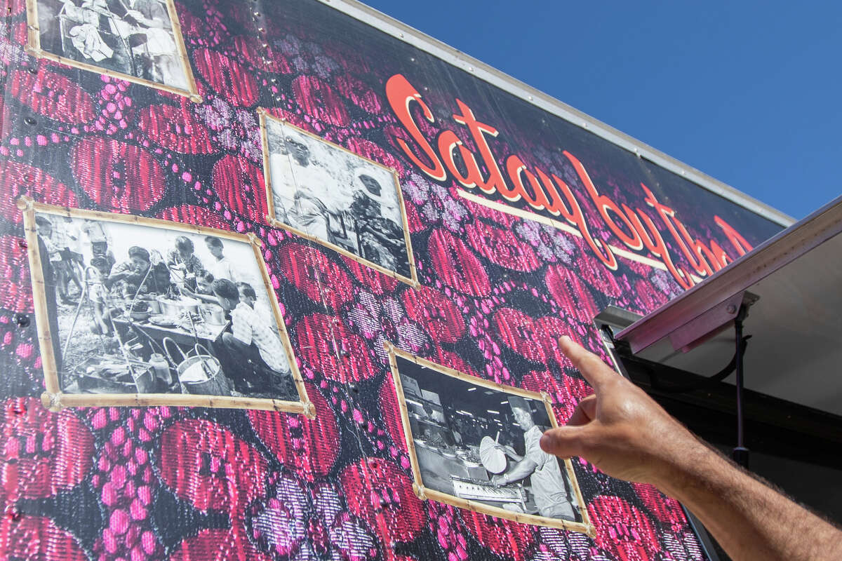 David Greenfield points out the photo of his wife Elly's grandparents reproduced on the side of their Satay by the Bay food truck at Off The Grid at Fort Mason in San Francisco, Calif. on Aug. 19, 2022. The Singaporean Halal food truck run by husband and wife couple Elly and David Greenfield.