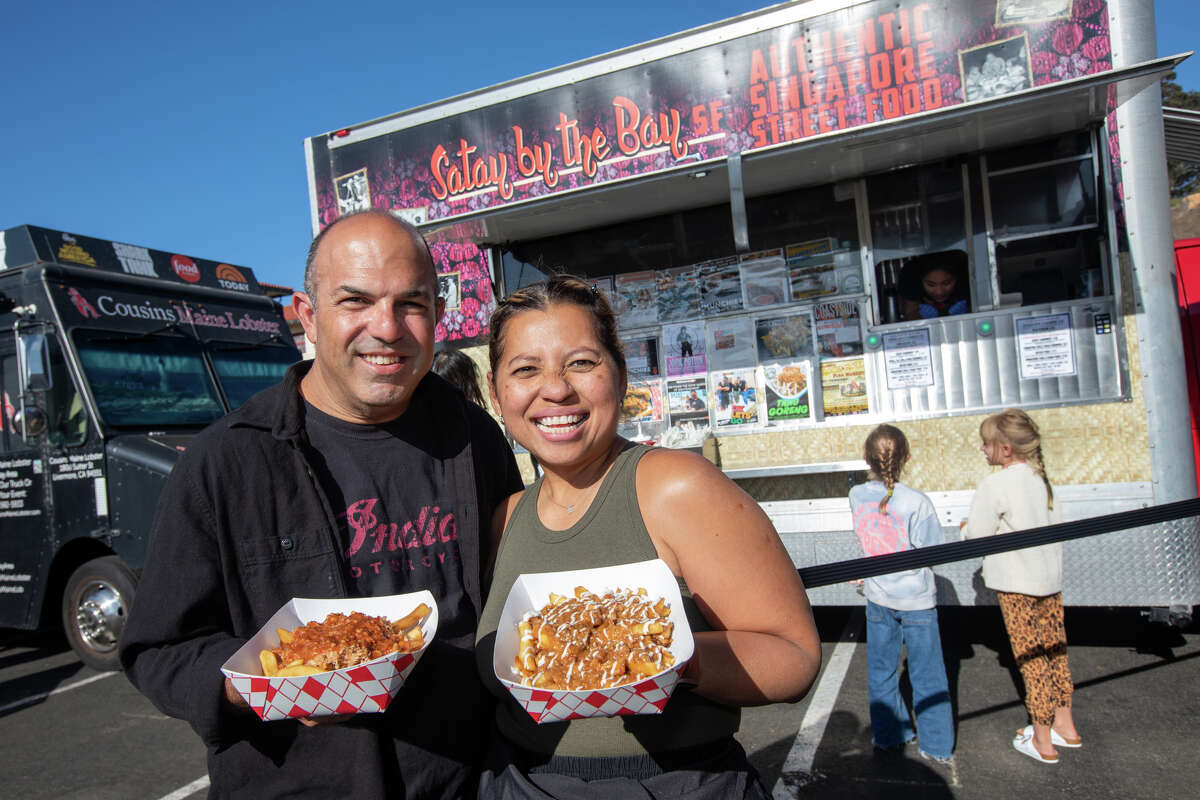 Satay by the Bay owners Elly and David Greenfield hold their chill crab fries and dutch fries in front of their food truck at Off The Grid at Fort Mason in San Francisco, Calif. on Aug. 19, 2022.