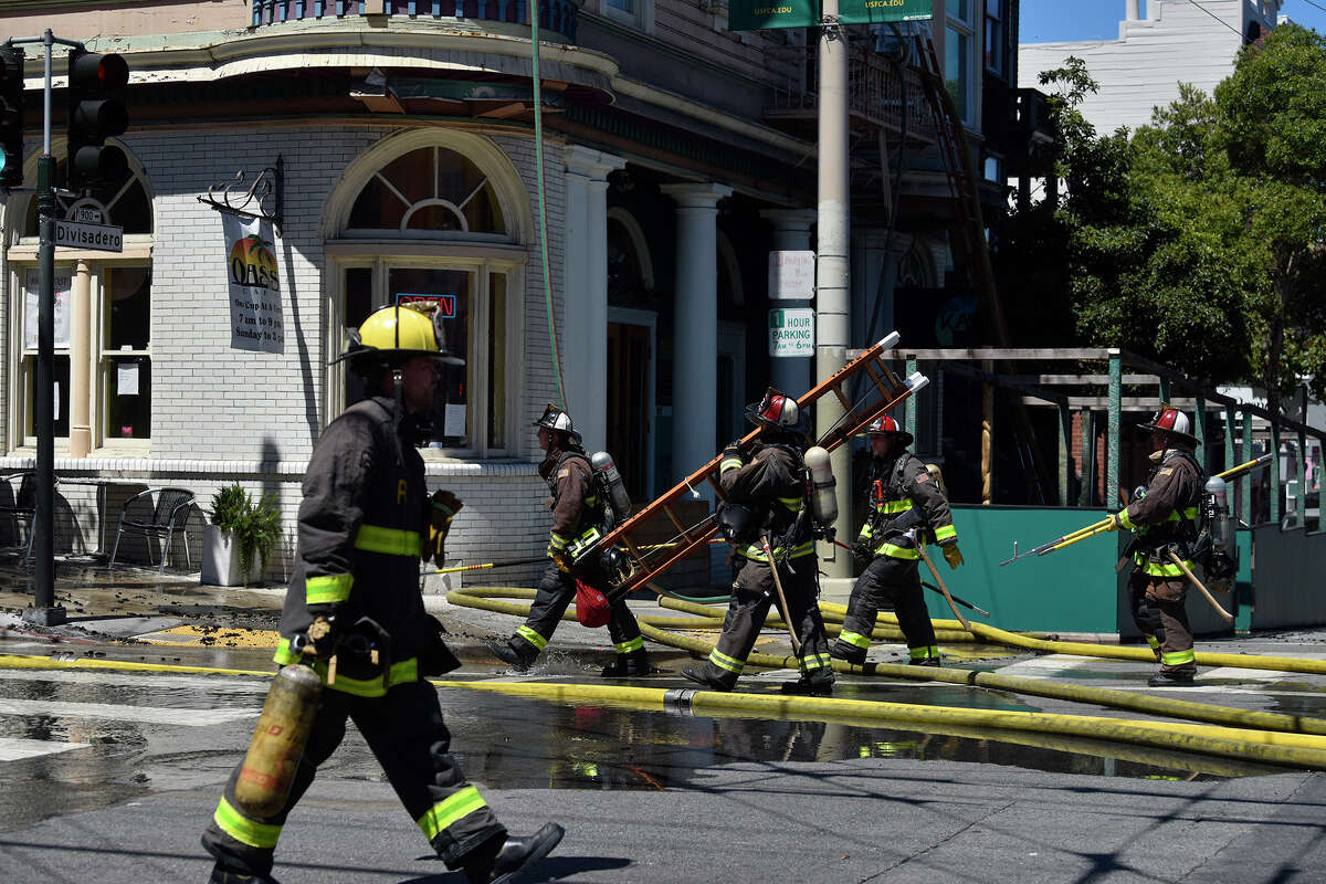 Members of the San Francisco Fire Department are seen responding to a three-alarm fire at 1604 McAllister St., at the intersection of Divisadero, on Aug. 23, 2022. Oasis Cafe is located on the ground floor level of the building.