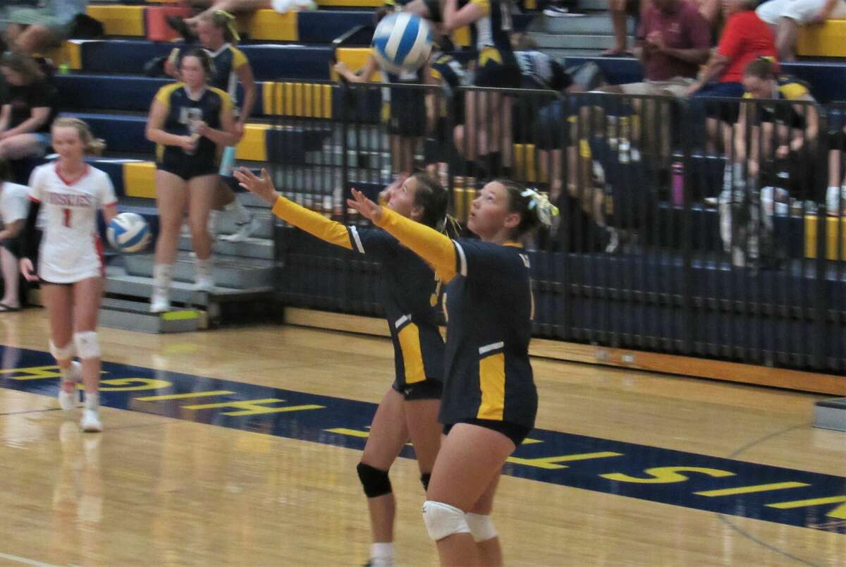 Manistee's Gracie Shivley (left) and Madelyn Wayward (right) practices serves during warm ups prior to a match against Benzie Central on Aug. 23.