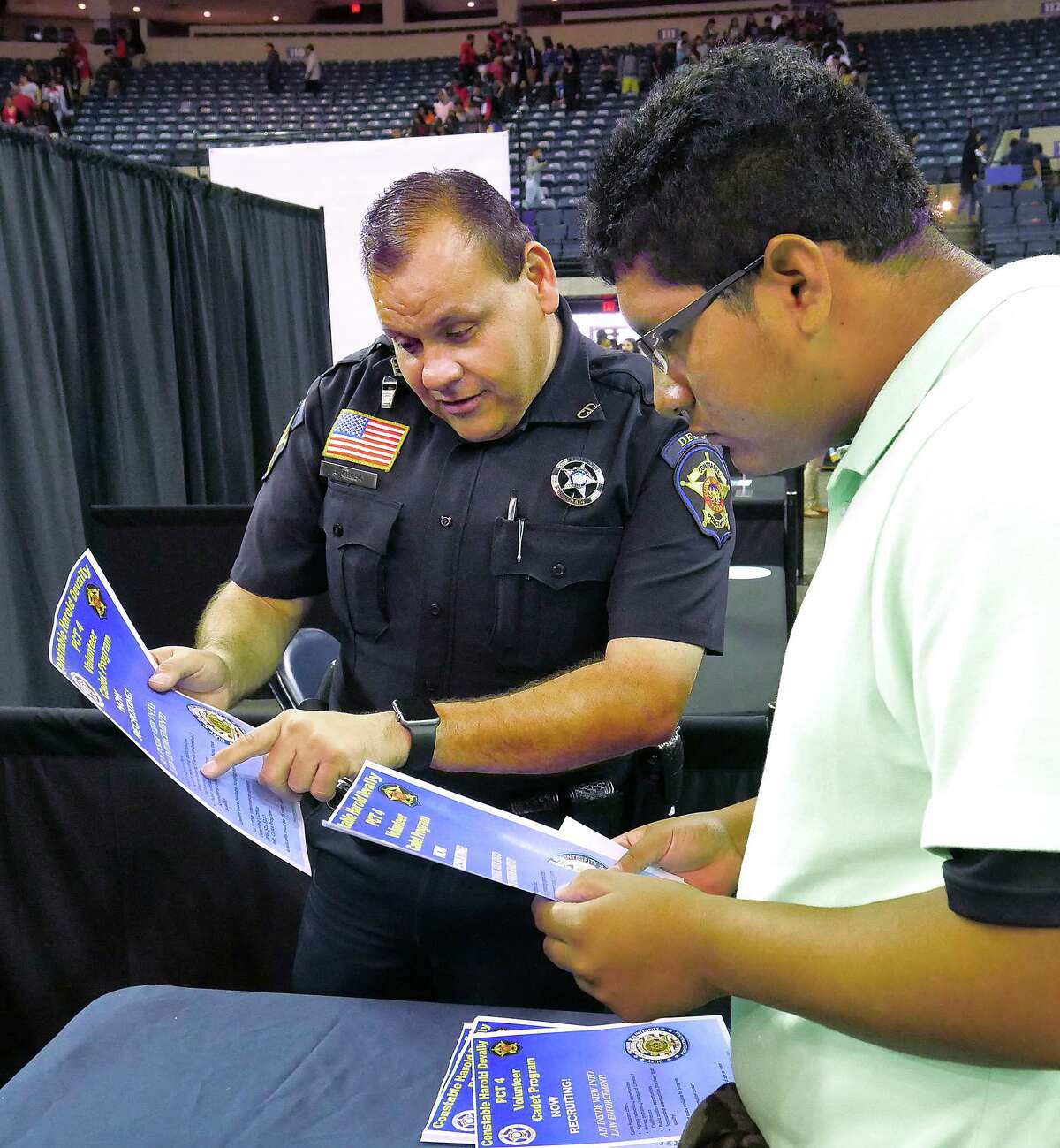 FILE — Precint 4 Deputy Constable Abraham Chapa and Nixon High School student Angel Flores go over the requirements needed to acquire a job with as a deputy at the South Texas WorkForce Solutions Youth Career Exploration Fair at the Sames Auto Arena, Wednesday, September 12, 2018.