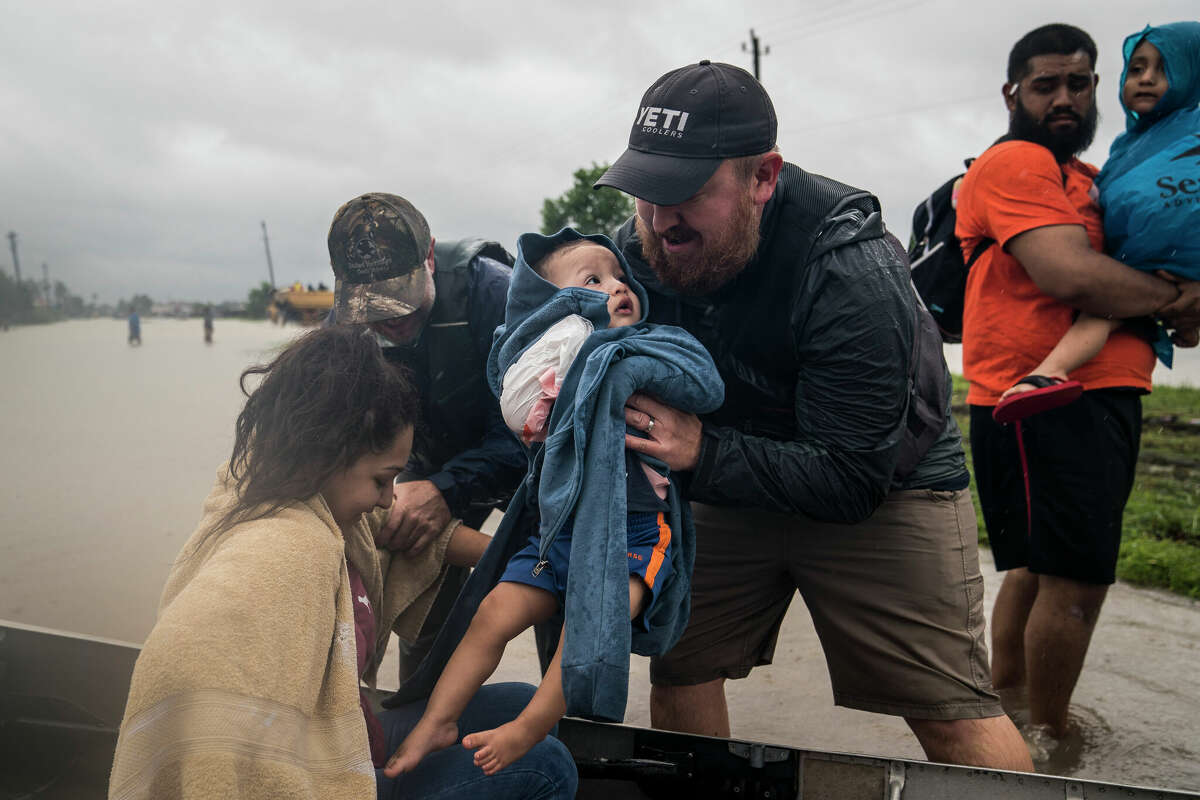 Glenda Montelongeo, Richard Martinez and his two sons are helped out of a boat after being rescued near Tidwell Road and Toll Road 8 in Houston, TX on Tuesday, Aug 29, 2017.
