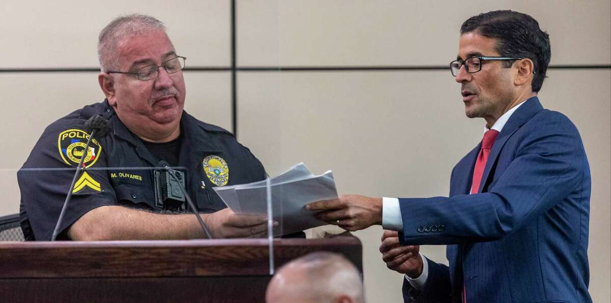 Police officer Mark Olivares, left, looks at documents from attorney Nicholas “Nico” LaHood as Olivares testifies in the 226th District Court in the Cadena-Reeves Criminal Justice Center during the public corruption trial of former Bexar County Constable Michelle Barrientes Vela on Wednesday, Aug. 24, 2022. Vela is charged with two felony counts of tampering with evidence in connection with an Easter Sunday incident in 2019 at a West Side park, where she allegedly coerced a family into giving her $300 for security for a pavilion they had already paid for.
