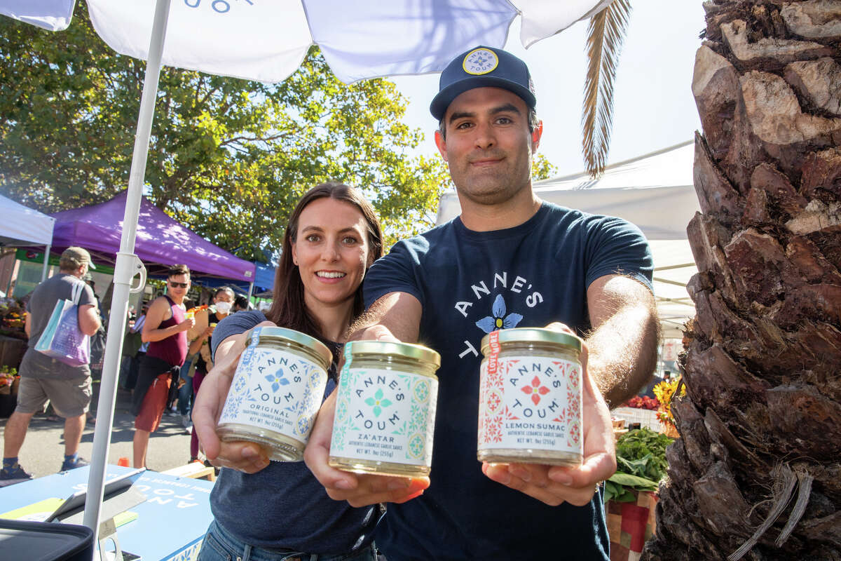 Owners Katia Berberi and husband Steve Drapeau hold some of their toum sauce at Anne's Toum stand at the Grand Lake farmer's market in Oakland, Calif. on Aug. 20, 2022. Their toum, a lebanese garlic sauce, is based on Katia's mother's family recipe.