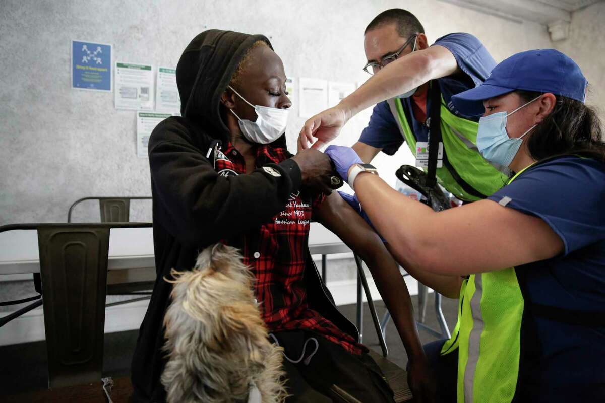 UCSF nurses prepare to administer a coronavirus booster to Lacrecia Hicks, who lives at a residential hotel in San Francisco's Tenderloin. In the latest milestone, 12,000 Californians now have been infected by COVID.