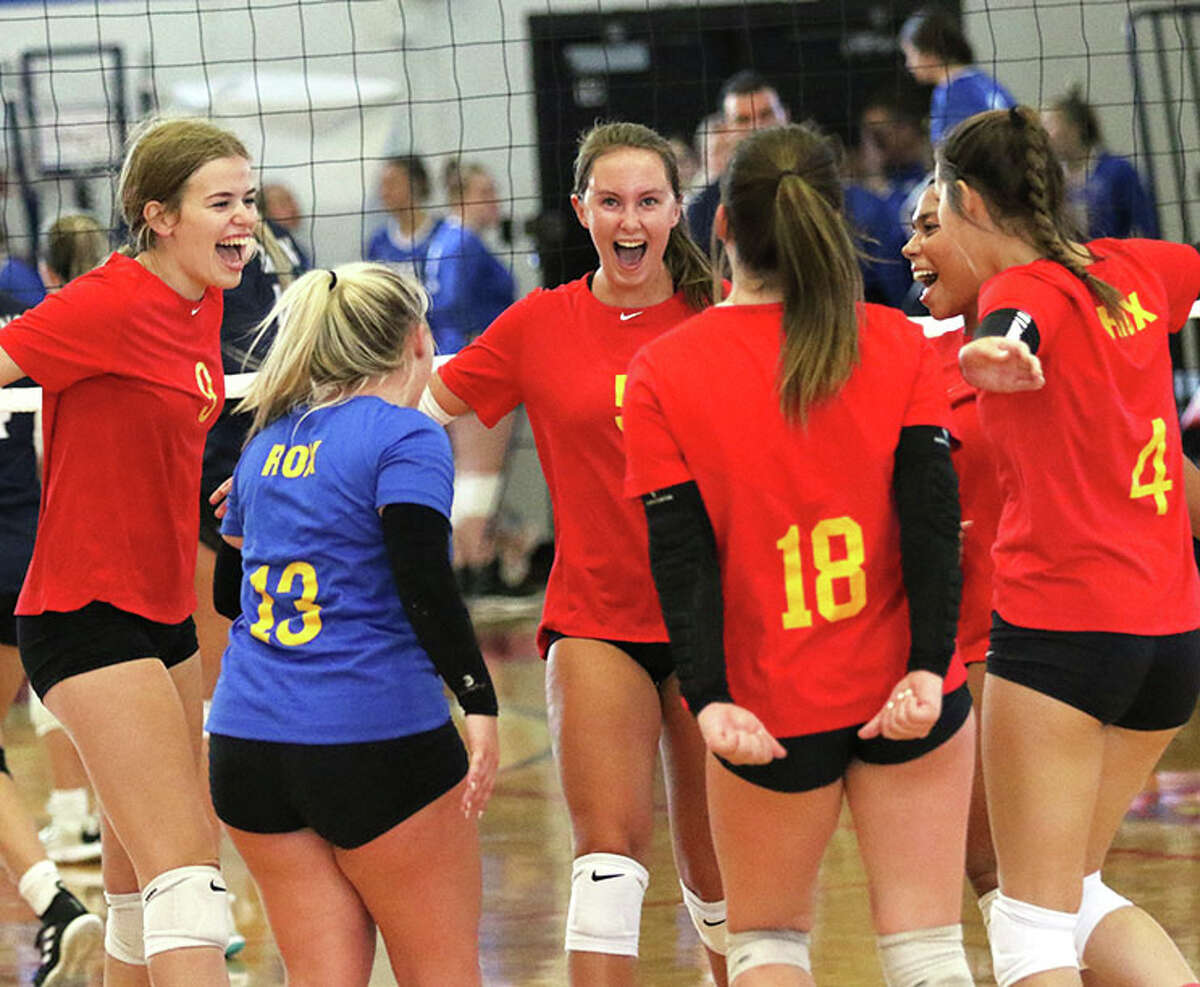 Roxana Abby Gehrs (left) and Lily Daugherty (middle) celebrate a point with teammates in their win over Father McGivney on Monday at the Roxana Invite.