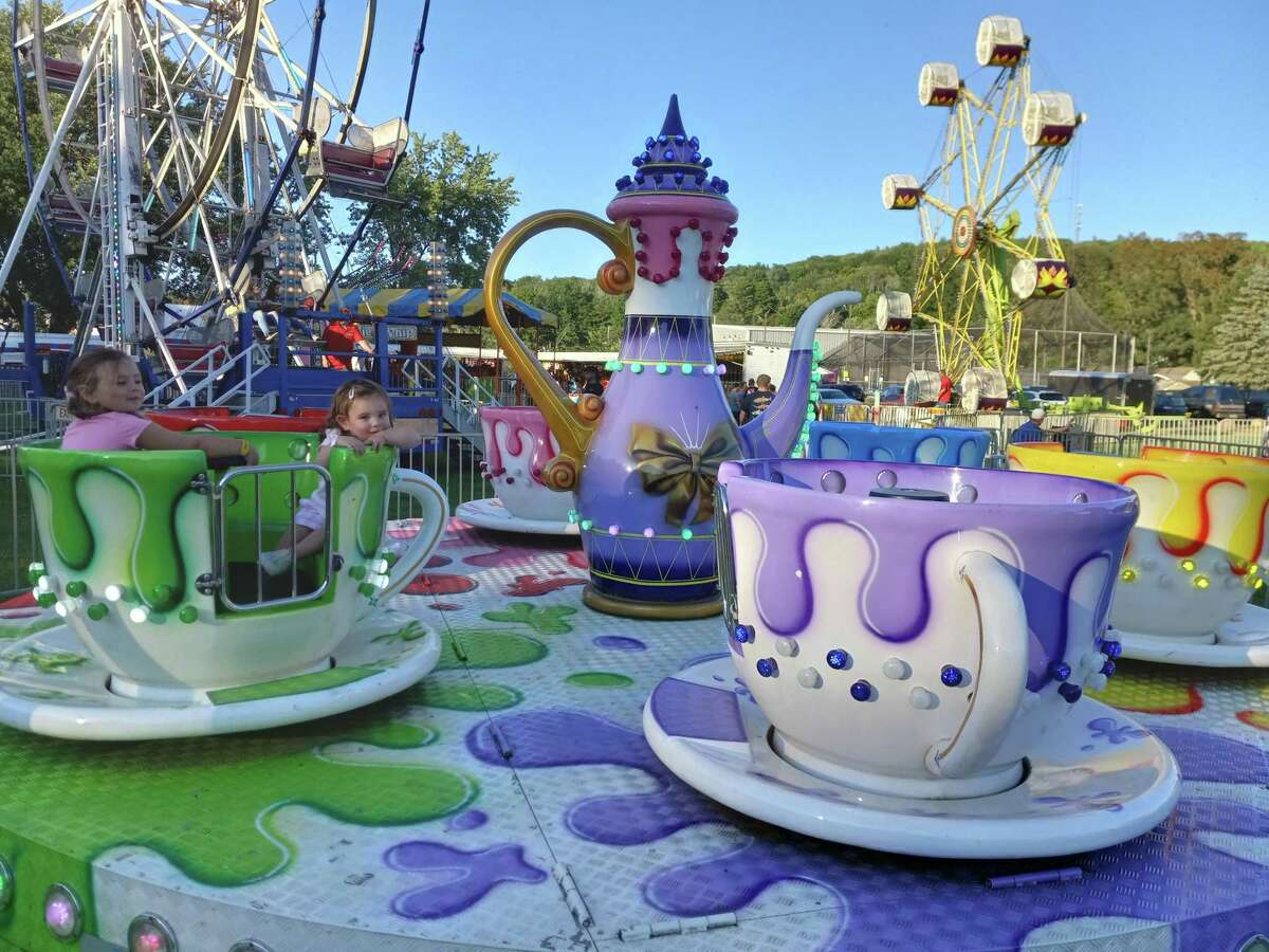 Olivia and Lucy Melycher ride the spinning teacups at the Winsted Fire Department’s annual carnival at Rowley Field.