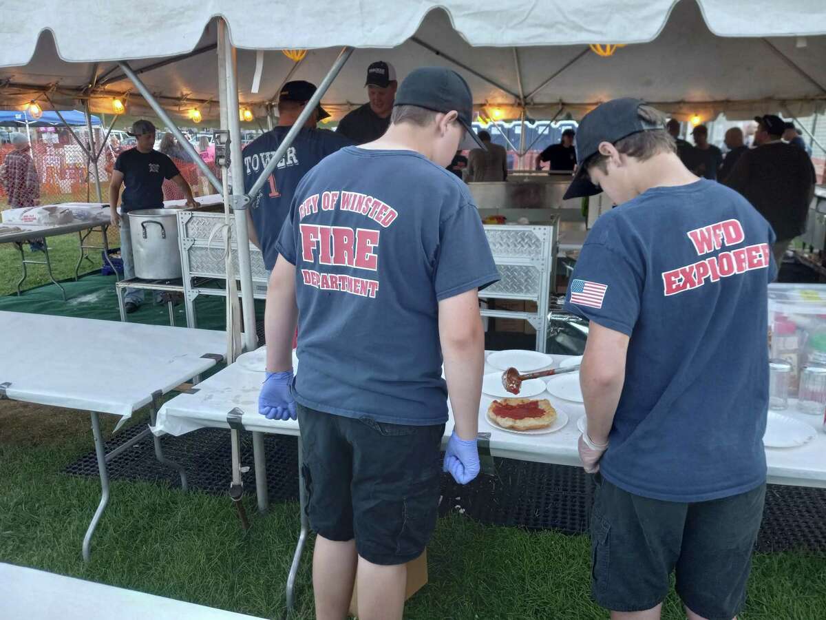 Members of the Winsted Fire Department prepare fried dough for a customer at the department’s annual carnival at Rowley Field.