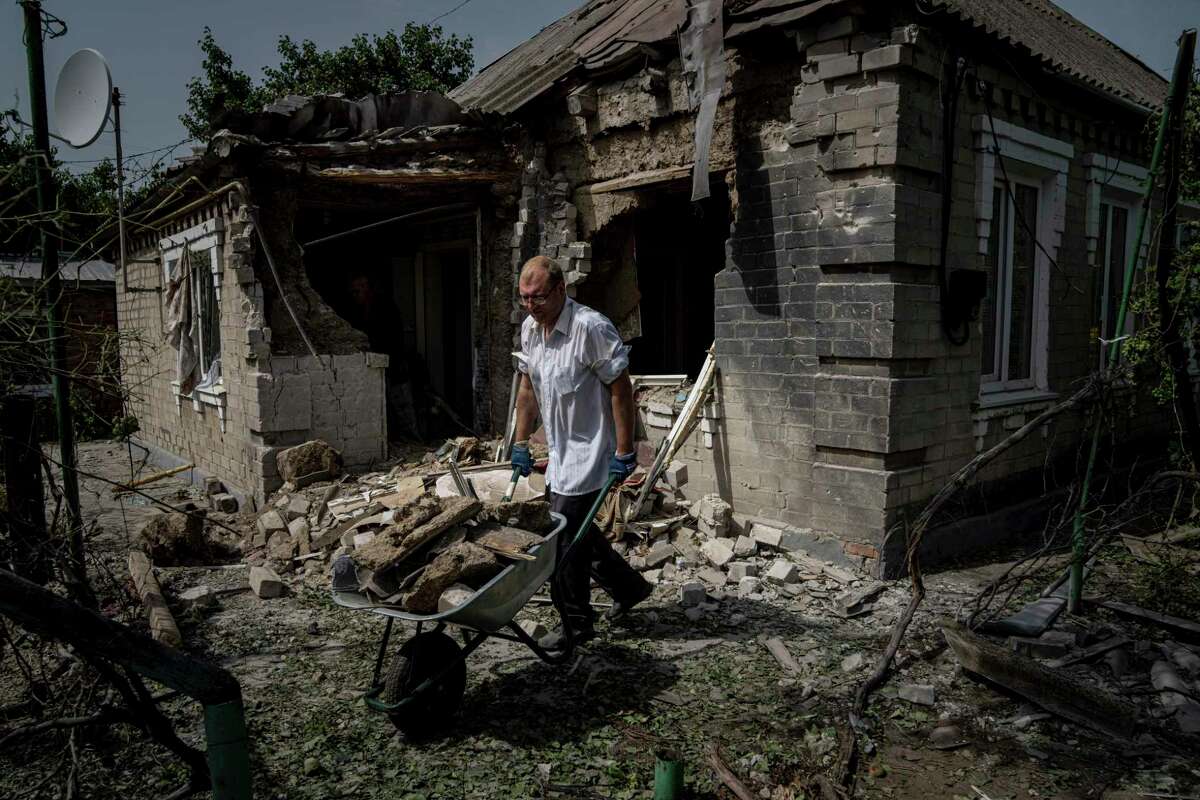 A man cleans rubble in front of the house damaged from a Russian bombardment in Nikopol, Ukraine, across the river from Ukraine's main nuclear power plant. Without a peace plan for Ukraine, a nuclear threat looms. , on Aug, 22. Author William Lambers calls for an end to the Ukraine War.