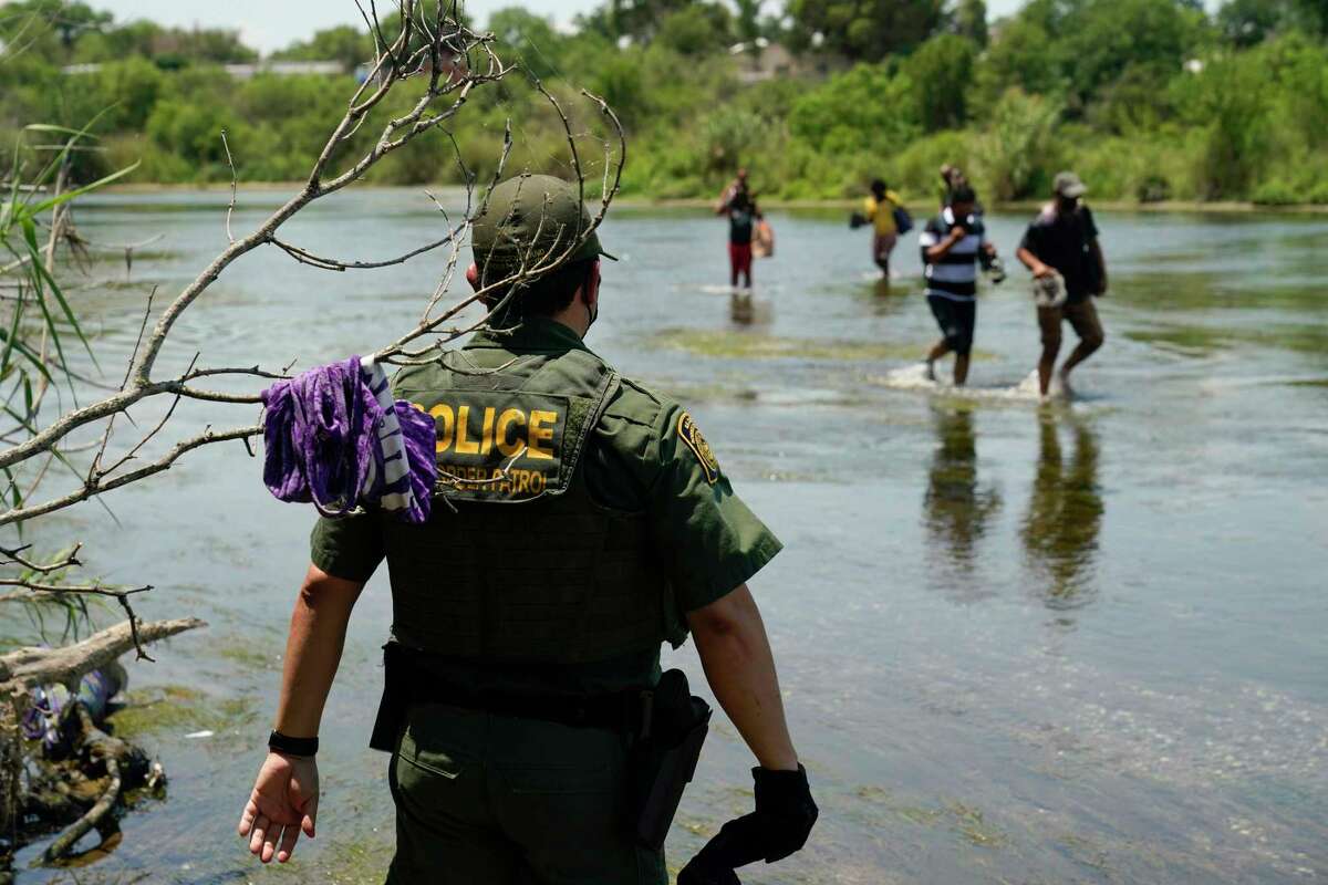 A Border Patrol agent watches in Del Rio as migrants walk across the Rio Grande on their way to turning themselves in.