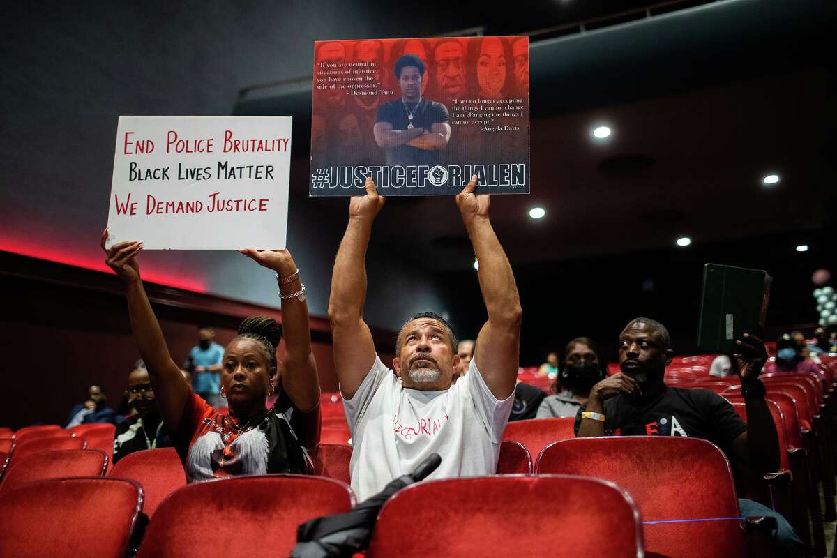 The mother, step-father and father of police-involved shooting victim Jalen Randle lift signs demanding justice at the National Bail Reform Panel Discussion event.