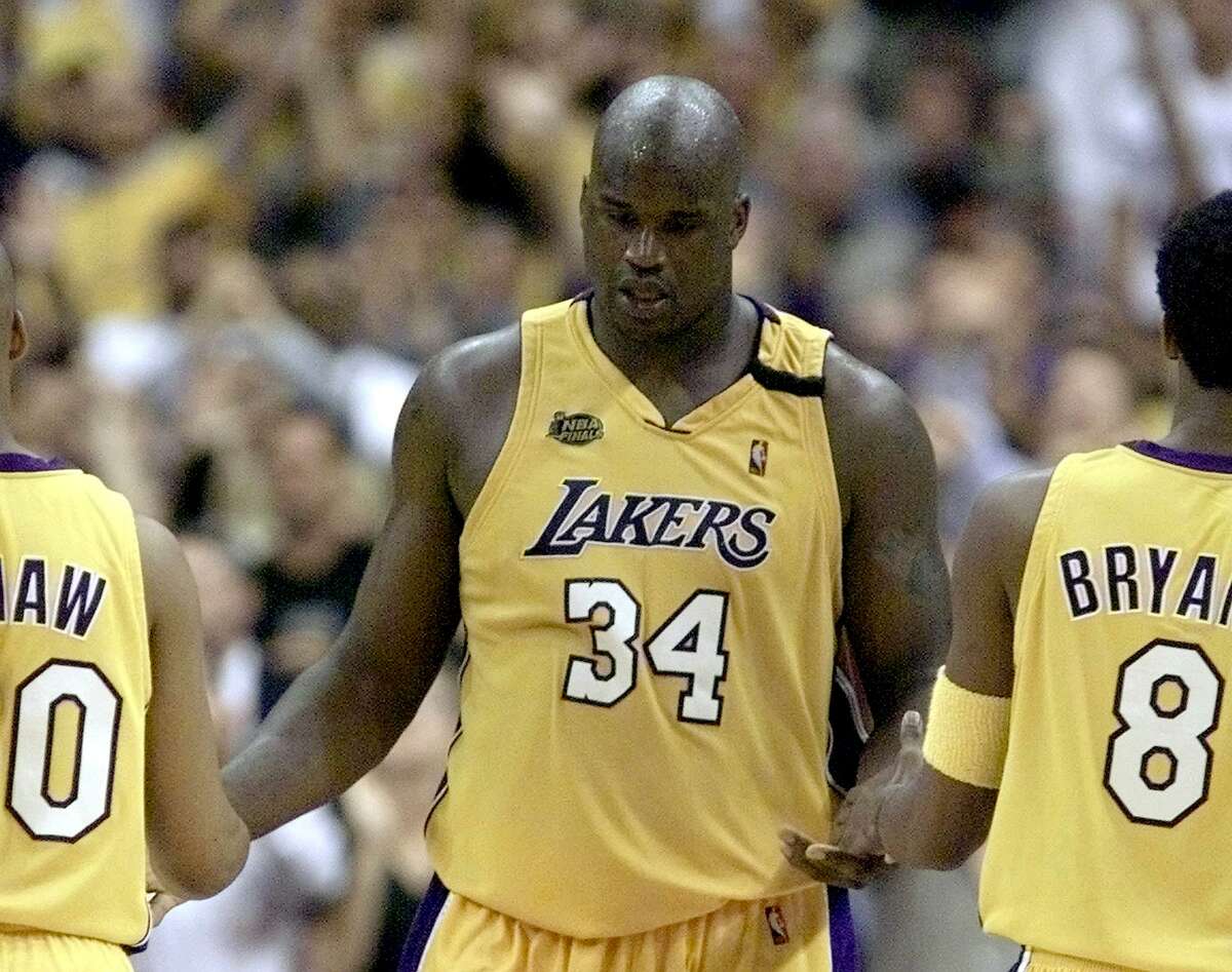 Shaquille O'Neal (C) of the Los Angeles Lakers is congratulated by teammates of Brian Shaw (L) and Kobe Bryant (R) 07 June, 2000, during the second half of game one of the NBA Finals games at Staples Centers in Los Angeles, CA. O'Neal finished the game with 43 points to lead the Laker to a 104-87 win to lead the best-of-seven game series 1-0. (ELECTRONIC IMAGE) AFP PHOTO/Jeff HAYNES (Photo by JEFF HAYNES / AFP) (Photo by JEFF HAYNES/AFP via Getty Images)