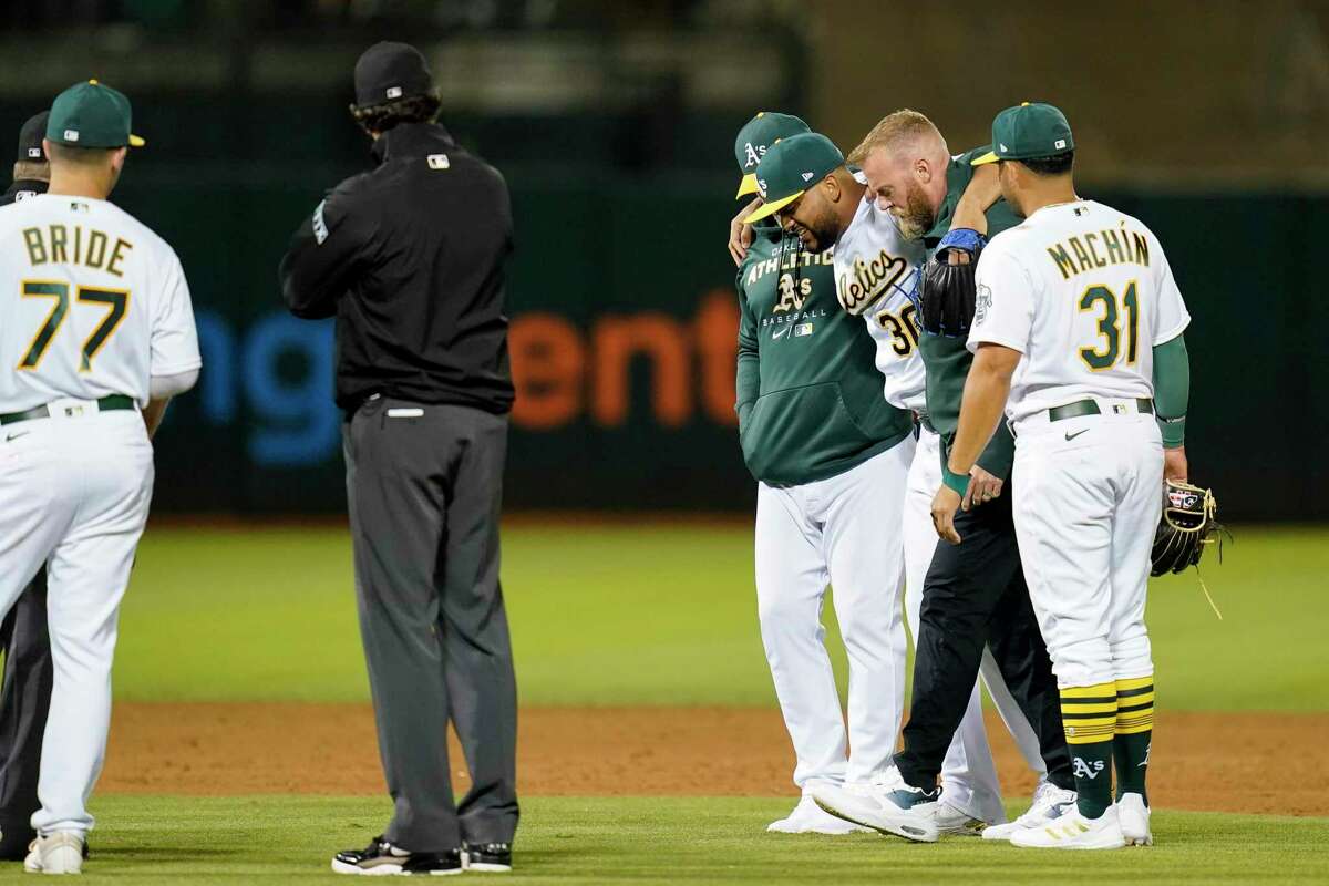 Oakland Athletics relief pitcher Joel Payamps (30) is helped off the field after being hit by a ball on a single hit by New York Yankees' Kyle Higashioka during the eighth inning of a baseball game in Oakland, Calif., Thursday, Aug. 25, 2022. (AP Photo/Godofredo A. Vásquez)