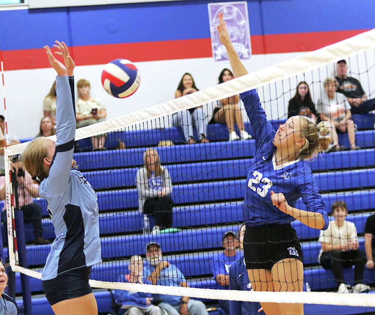 Marquette Catholic's Kylie Murray (right) hits past the Jersey block in Monday's pool play at the Roxana Tourney. On Thursday, Murray had nine kills in the Explorers' three-set win at Carrollton.