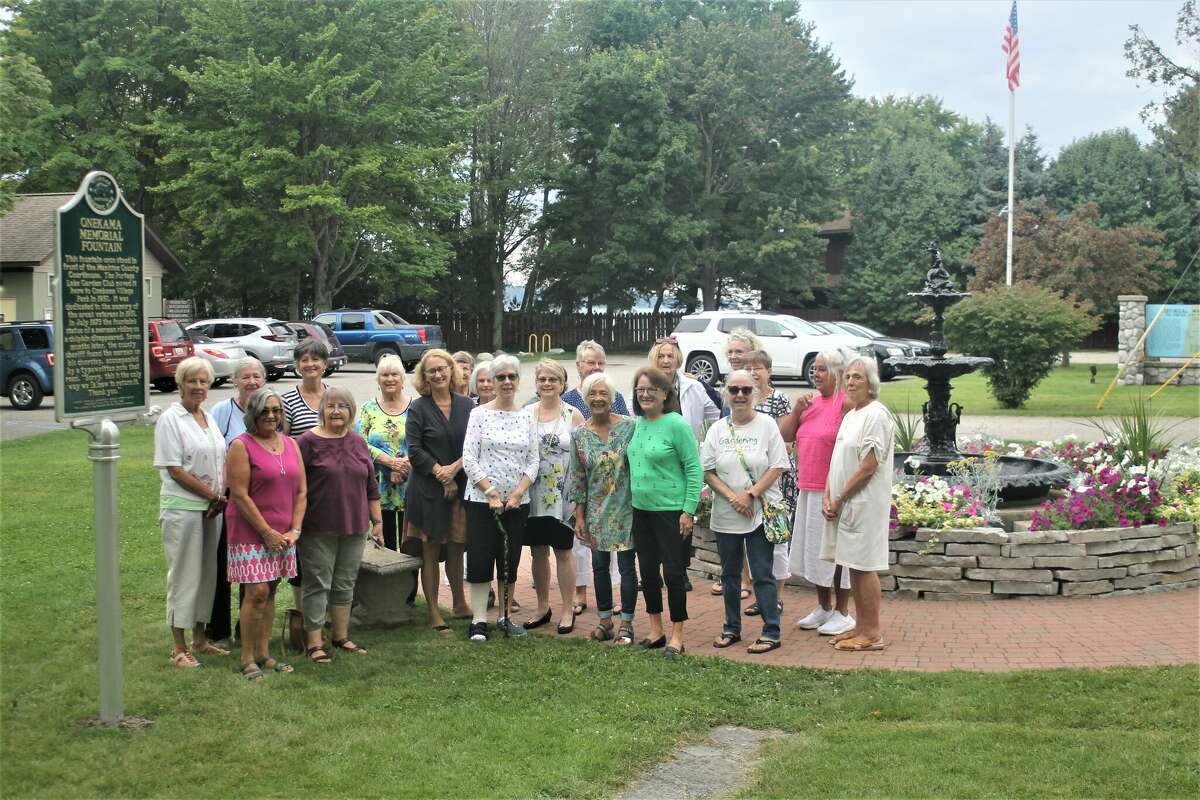 Portage Lake Garden Club members pose for a photo Thursday in Onekama Village Park between a Michigan historic marker and the Memorial Fountain for which it was installed.