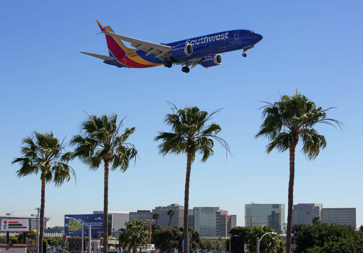 A Southwest flight soaring over an In-N-Out hamburger restaurant adjacent to a runway at Los Angeles International Airport.