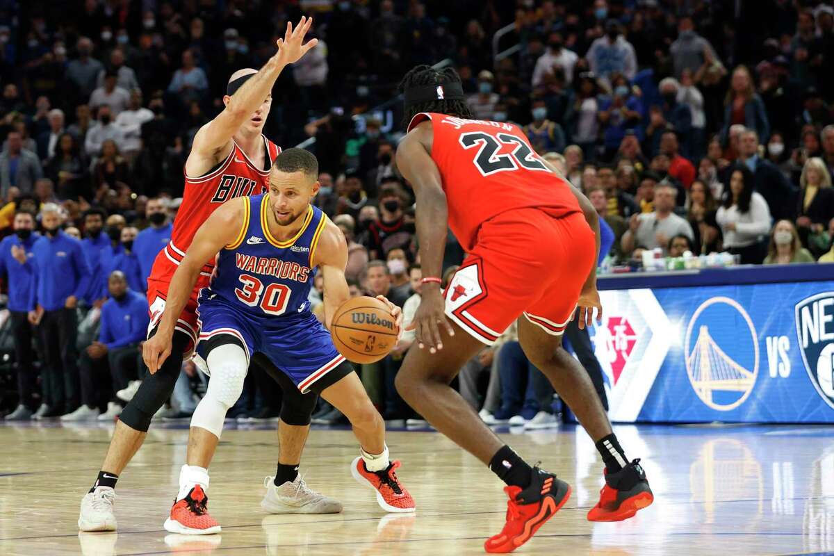 Golden State Warriors guard Stephen Curry drives towards the basket as Chicago Bulls guard Alex Caruso and forward Alize Johnson defends during the second quarter of their NBA basketball game in San Francisco, Calif. Friday, Nov. 12, 2021.