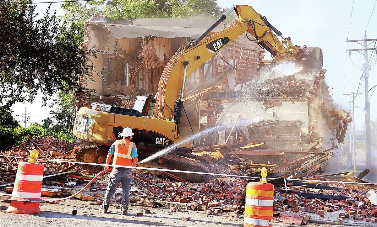 John Badman|The Telegraph A Stutz Excavating employee sprays water on the brick building being torn down Wednesday at the corner of East 4th and Ridge streets in Alton.