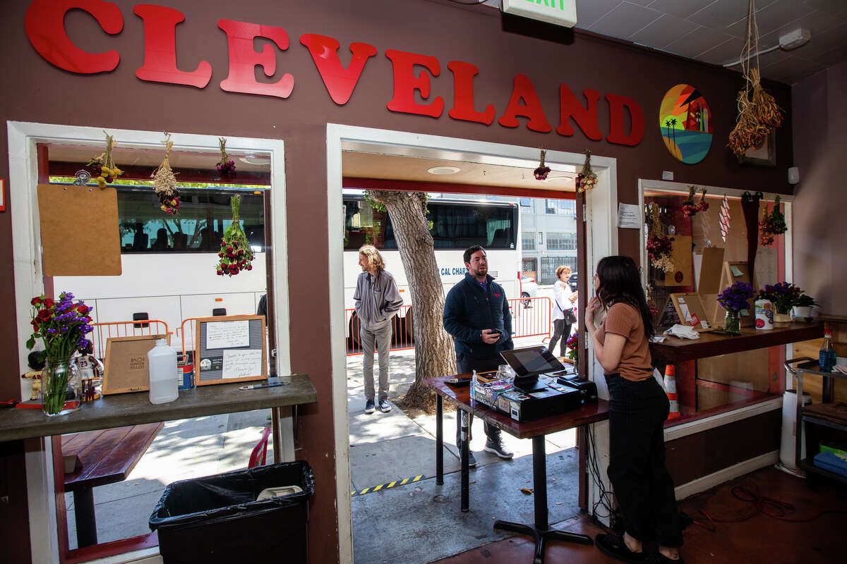 Employee Justice Stone takes orders from customers at the entryway of Deli Board in San Francisco, Calif. on Aug. 19, 2022. The deli used to have a dining room but the restaurant has been covered to take-out only since the start of the COVID-19 pandemic.