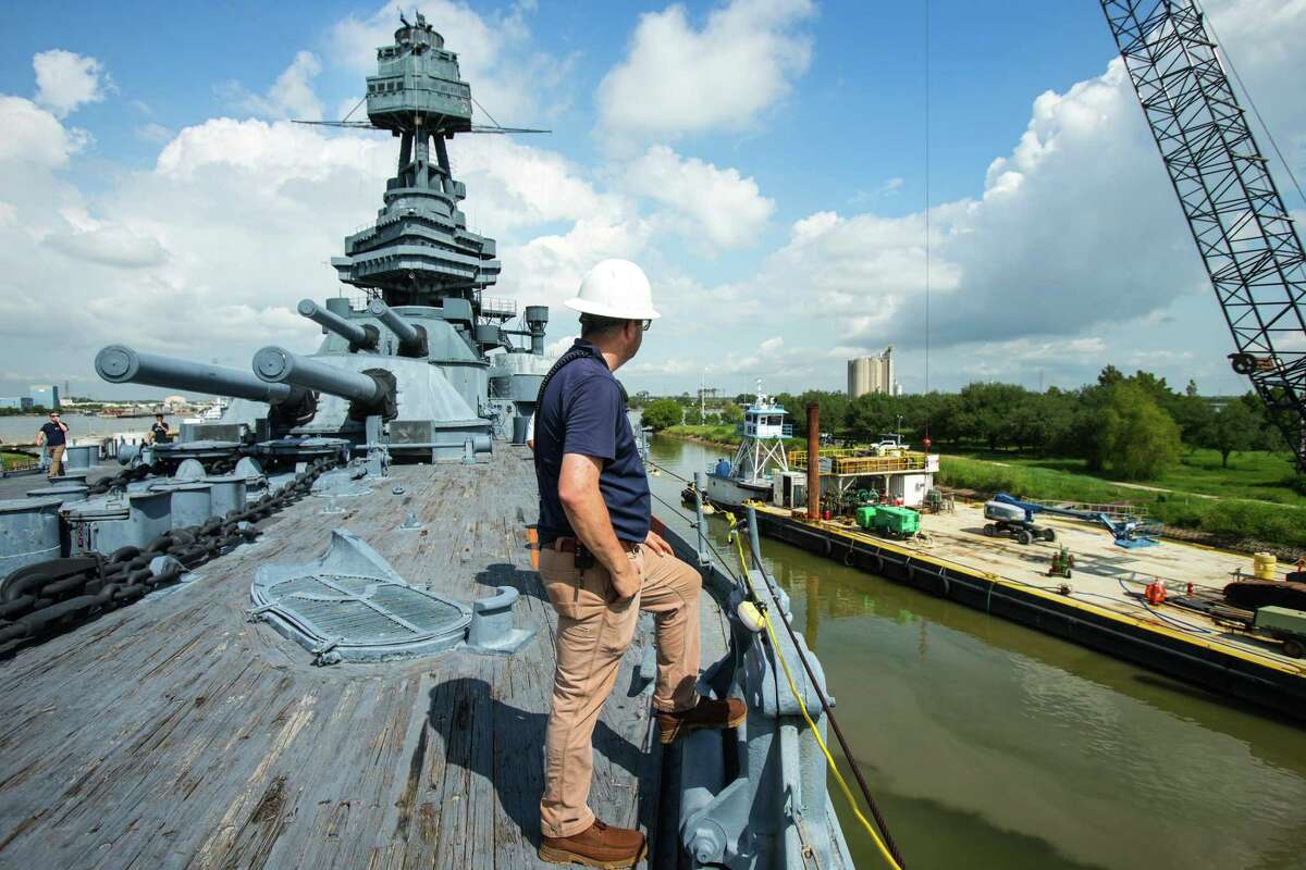 Travis Davis, vice president of ship operations for the Battleship Houston Foundation, stands on the deck as a crane barge floats in to move things aboard while preparing the ship for its move to a Galveston dry dock on Aug. 26, 2022 in La Porte. Officials plan to move the battleship on Aug. 31.