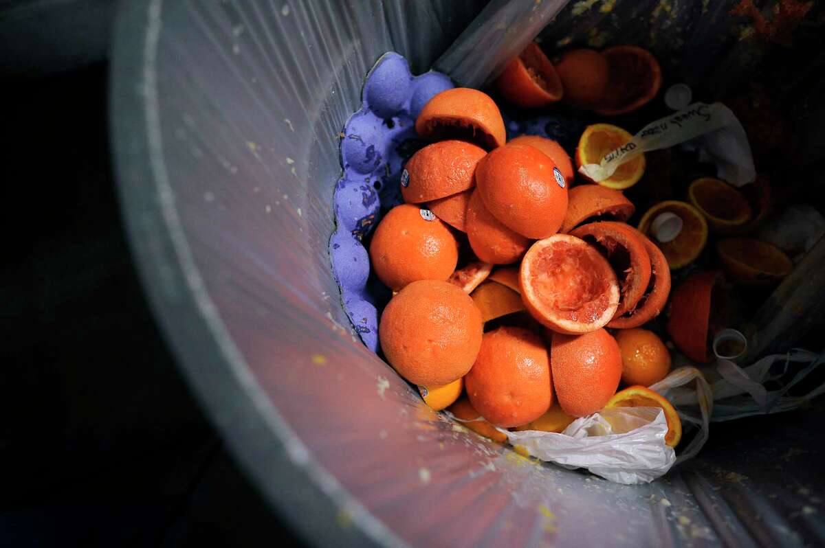 A garbage can full of juiced oranges destined for a landfill.