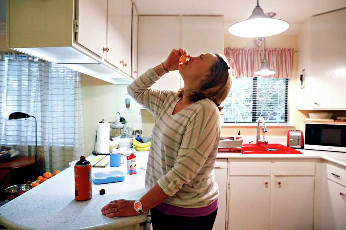 Lily Godsoe takes her daily dose of liquid tumeric at home in Half Moon Bay. Godsoe got COVID in March 2020 and has suffered for more then two years with long COVID. She said that although acupuncture helped relieve some symptoms last fall, it wasn’t until she bought a large bottle of high-potency turmeric elixir at Costco that her most vexing symptom — deep lung pain — vanished.