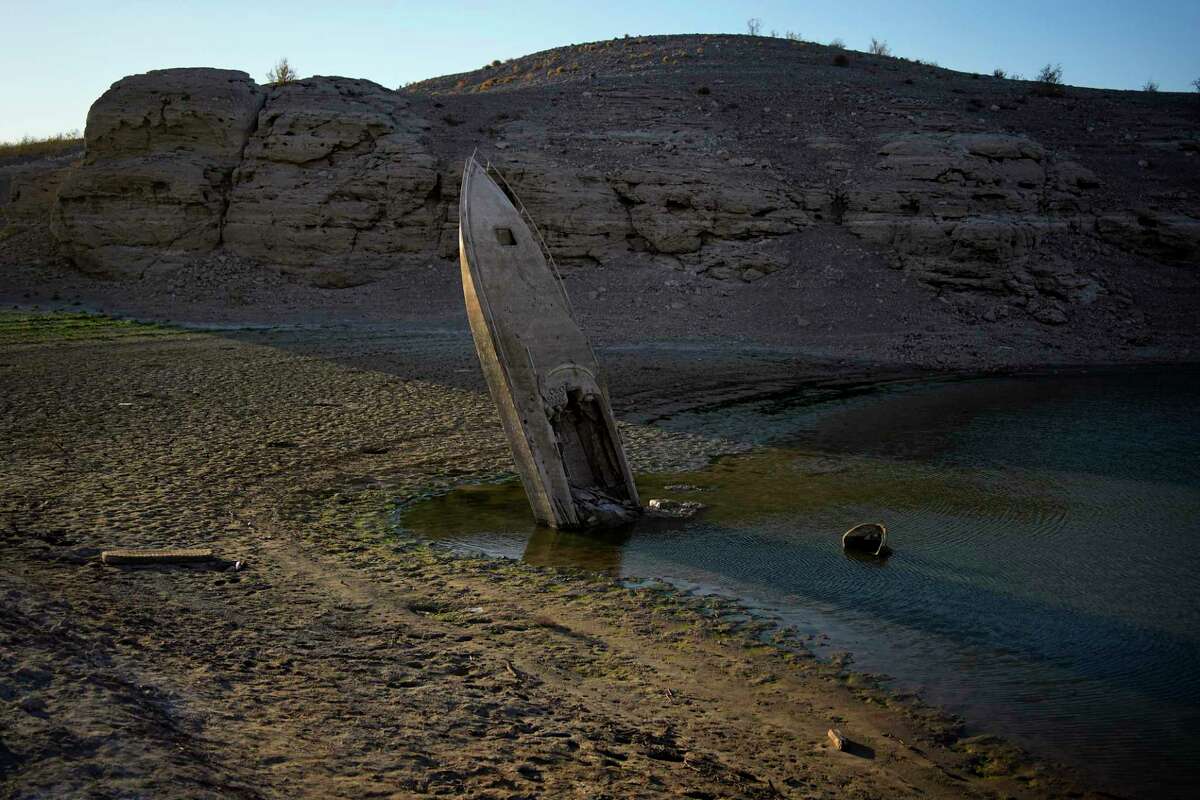FILE - A formerly sunken boat sits upright into the air with its stern stuck in the mud along the shoreline of Lake Mead at the Lake Mead National Recreation Area, Friday, June 10, 2022, near Boulder City, Nev. The identification of bones found in May on the receding shoreline of Lake Mead has resurfaced family memories of a 42-year-old Las Vegas father believed to have drowned 20 years ago.
