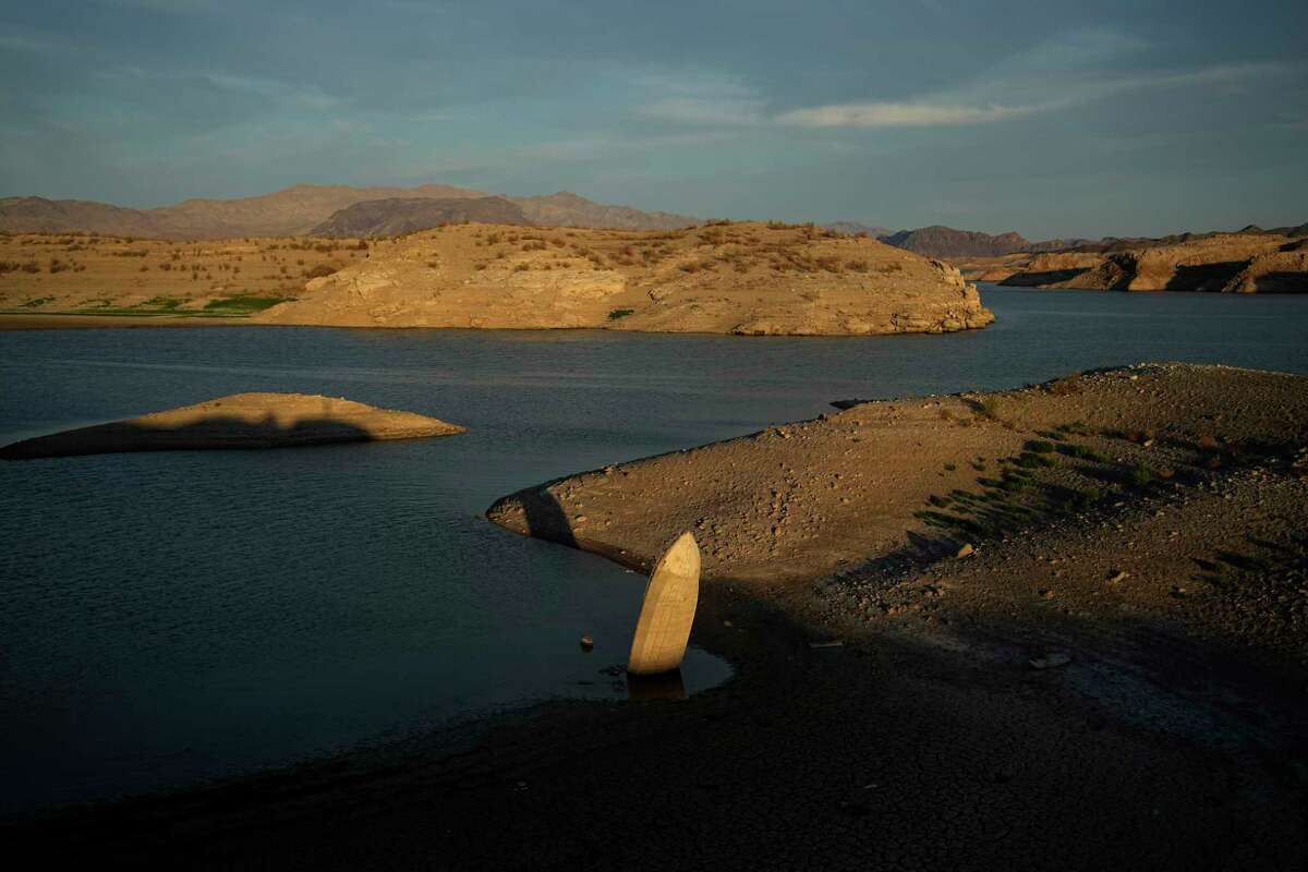FILE - A formerly sunken boat sits upright into the air with its stern stuck in the mud along the shoreline of Lake Mead at the Lake Mead National Recreation Area, on June 10, 2022, near Boulder City, Nev. Authorities in Las Vegas have identified bones found in May along newly exposed Lake Mead shoreline as the remains of a 42-year-old Las Vegas man who is believed to have drowned 20 years ago. The Clark County coroner's office said Wednesday, Aug. 24, 2022, that Thomas Erndt was reported missing in August 2002.