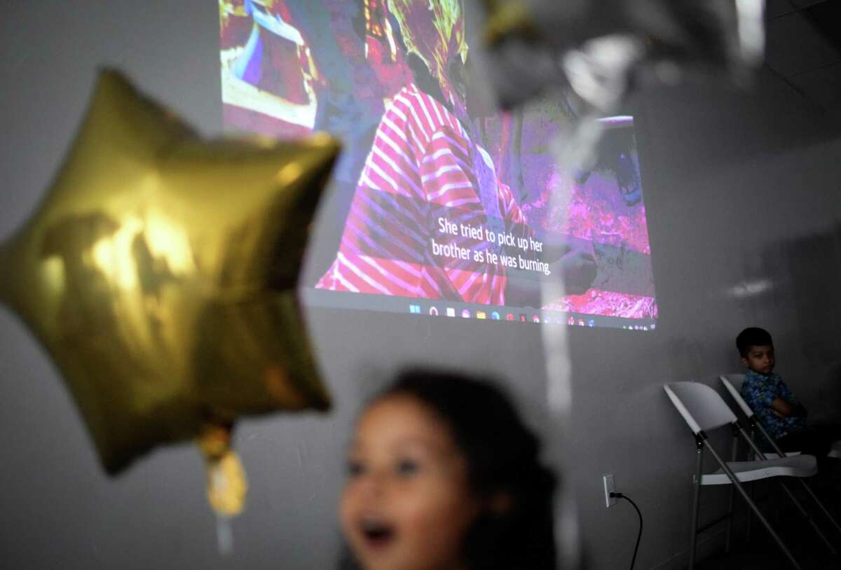 A young girl plays obliviously as people watch a video about the Rohingya genocide during a remembrance event Saturday, Aug. 27, 2022, in Houston.